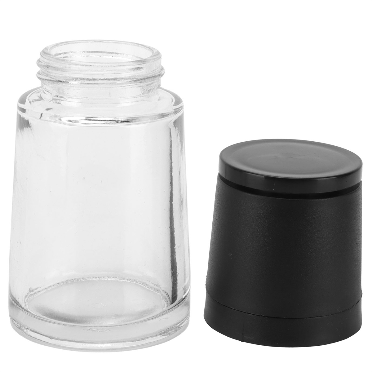 Ein klares Glas mit einem schwarzen Deckel ist offen, neben einem abgenommenen schwarzen Deckel.