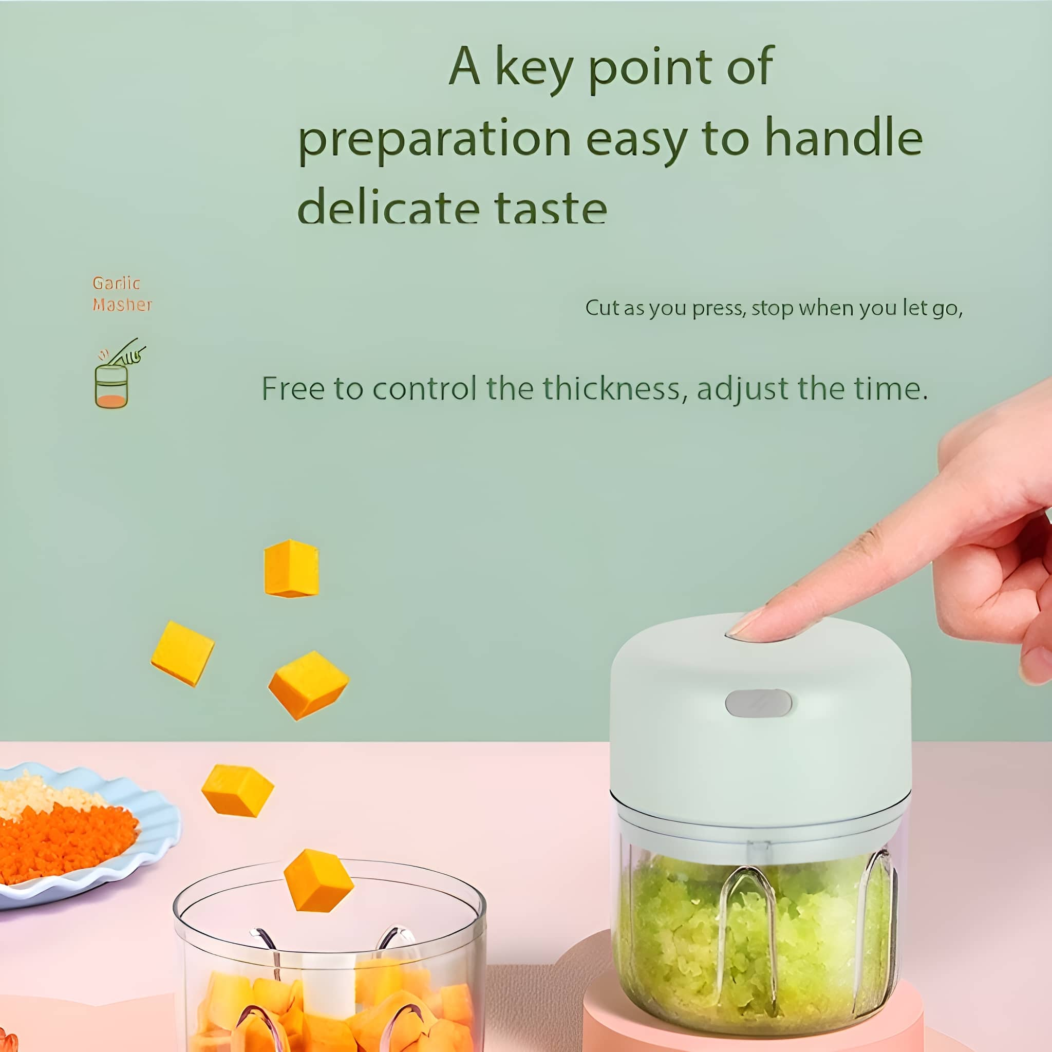 Ein kleiner grüner Foodprozessor mit gehackten Lebensmitteln. Eine Hand drückt einen Knopf. Ein klarer Behälter.