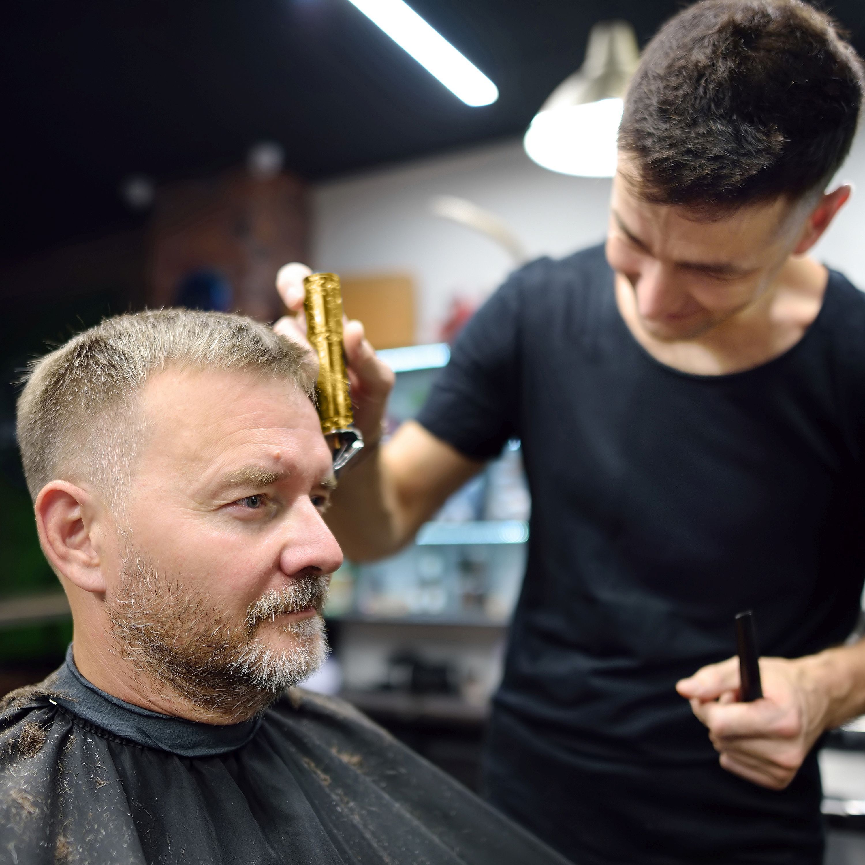 Ein Friseur schneidet einem Mann im Friseursalon die Haare mit einer Haarschneidemaschine.
