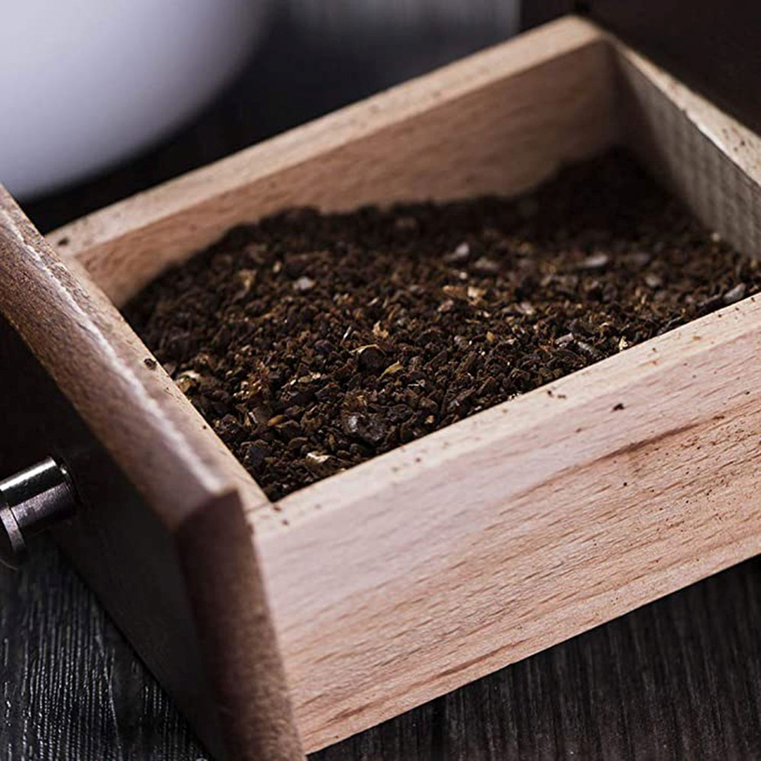 Eine Holzkiste ist mit Kaffeepulver gefüllt. Die Kiste ist offen und zeigt das dunkle Pulver.