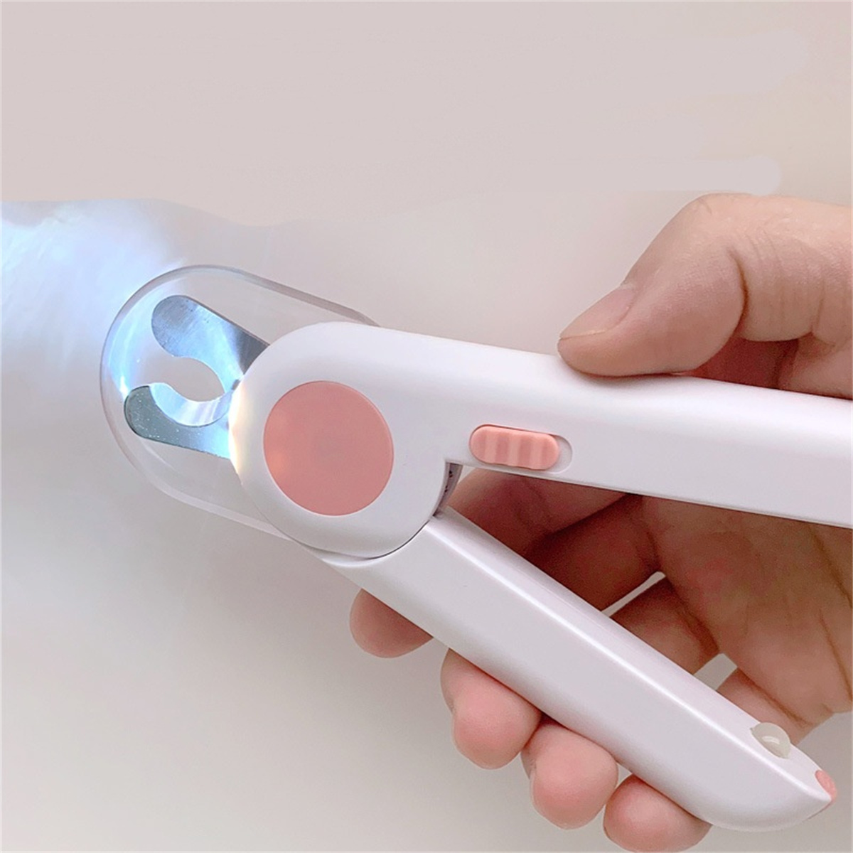Eine Person hält einen Nagelknipser mit Licht. Der Clipper ist weiß mit pinkfarbenem Knopf und Details.