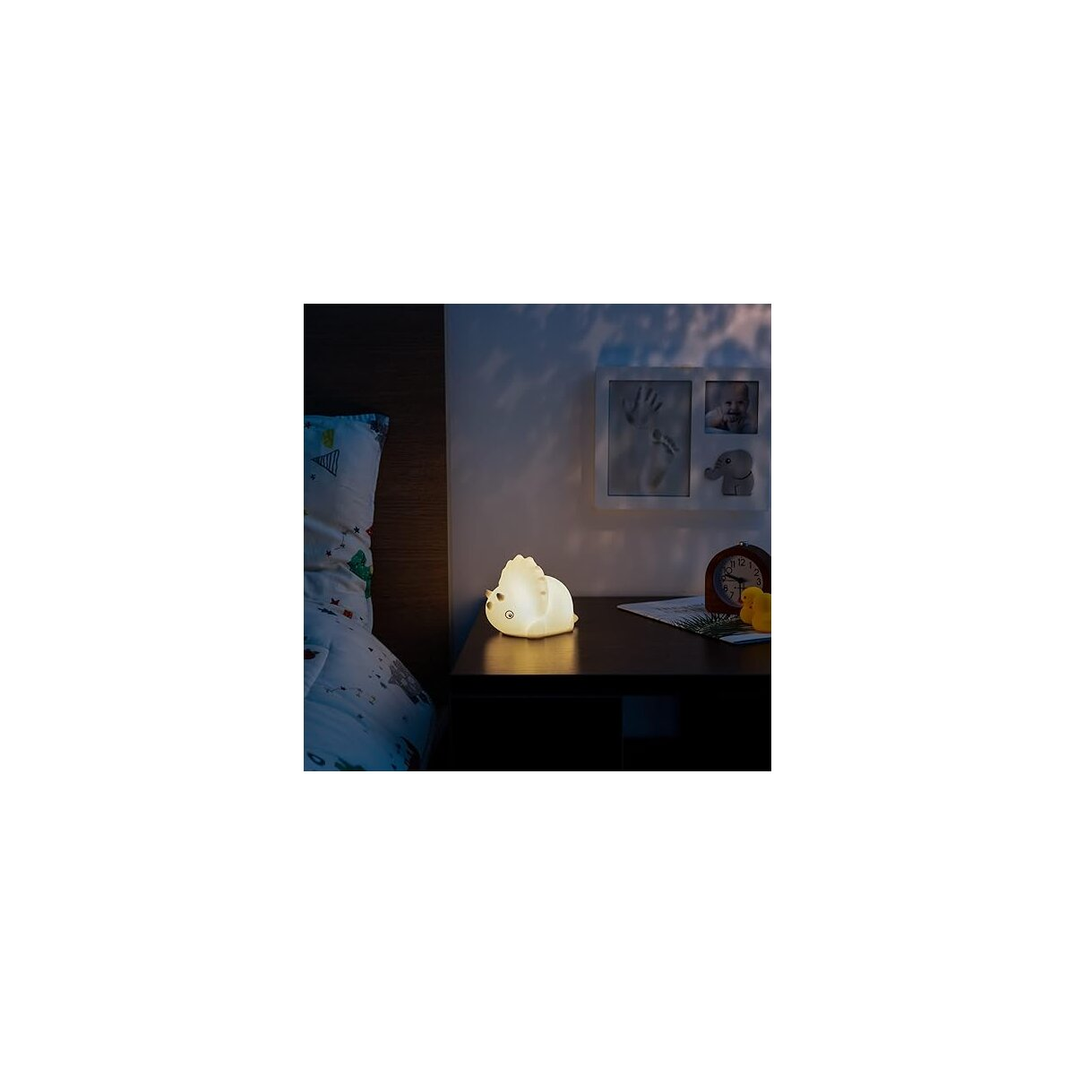 Ein Nachttisch mit einer leuchtenden Igel-Lampe, Bilderrahmen und einer Uhr.