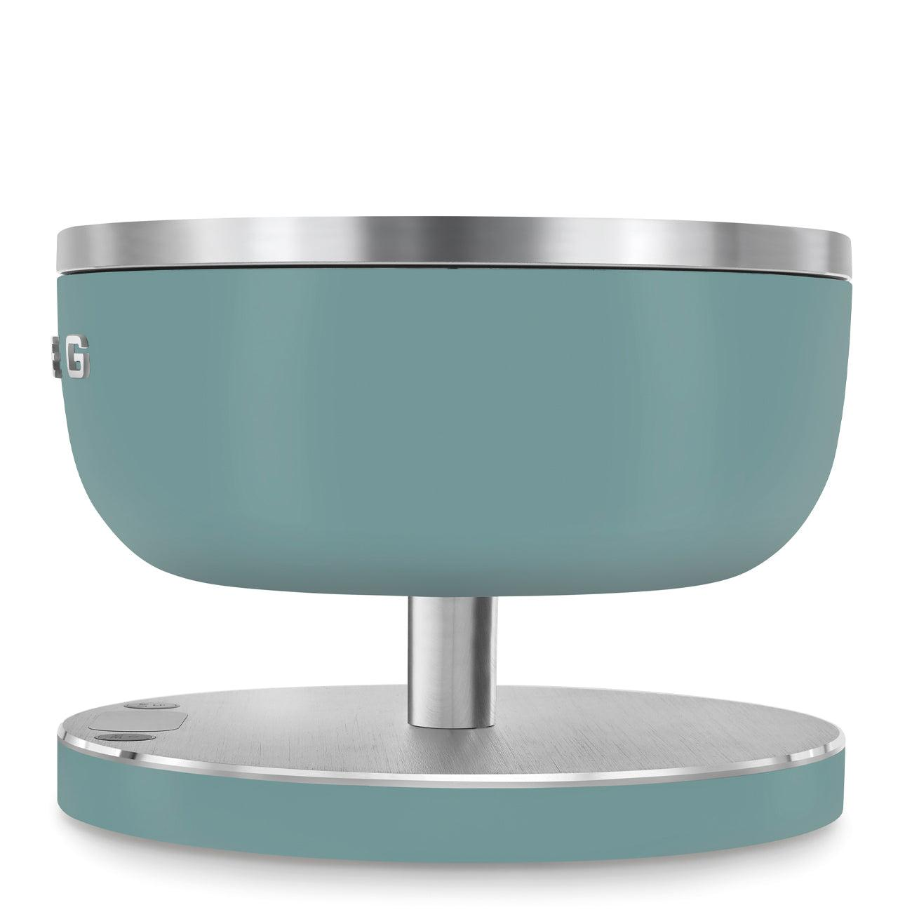 Turkusowy obiekt w kształcie miski na srebrnym stojaku ze srebrną obręczą i podstawą, białe tło.