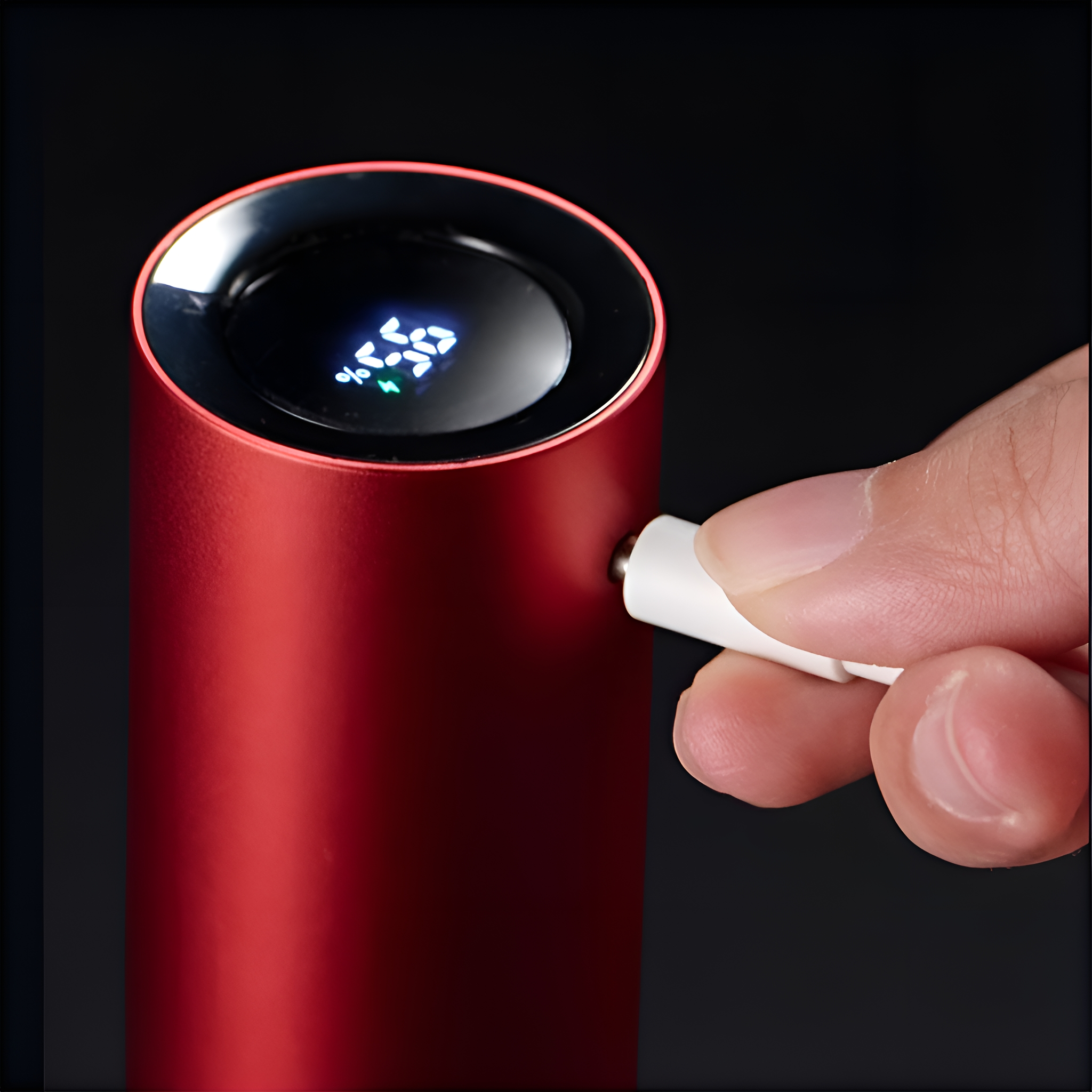 Rotes zylindrisches Gerät mit Digitalanzeige wird mit weißem Kabel geladen.