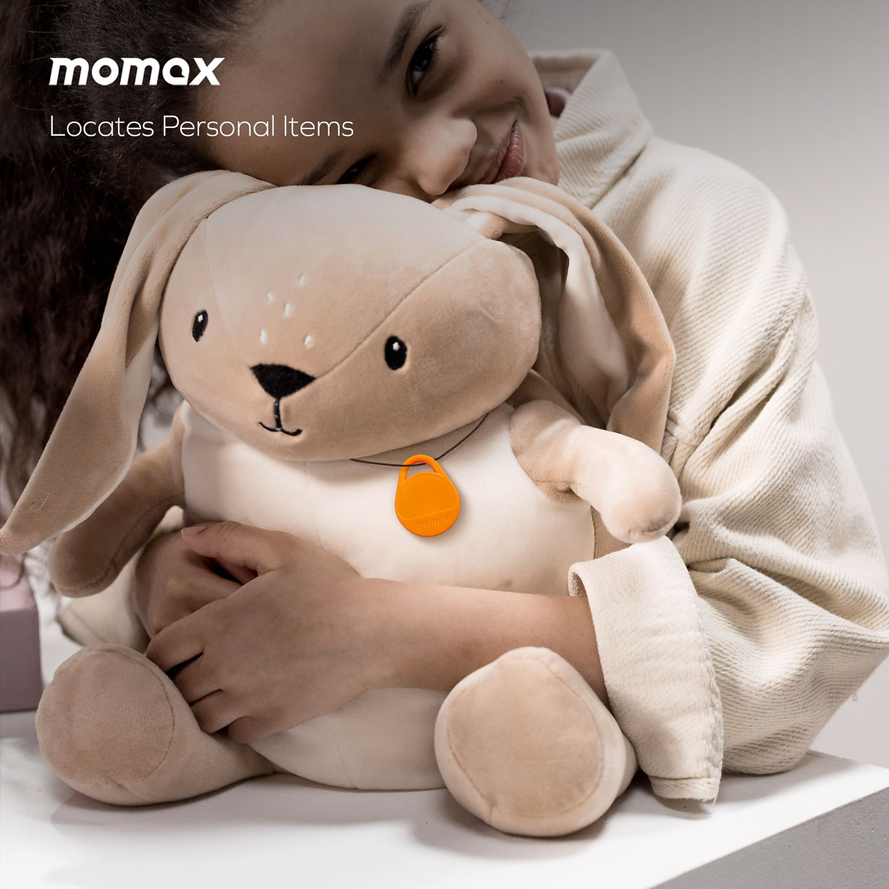 Girl hugging a stuffed bunny with an orange tag. Bunny is beige. Background is beige.