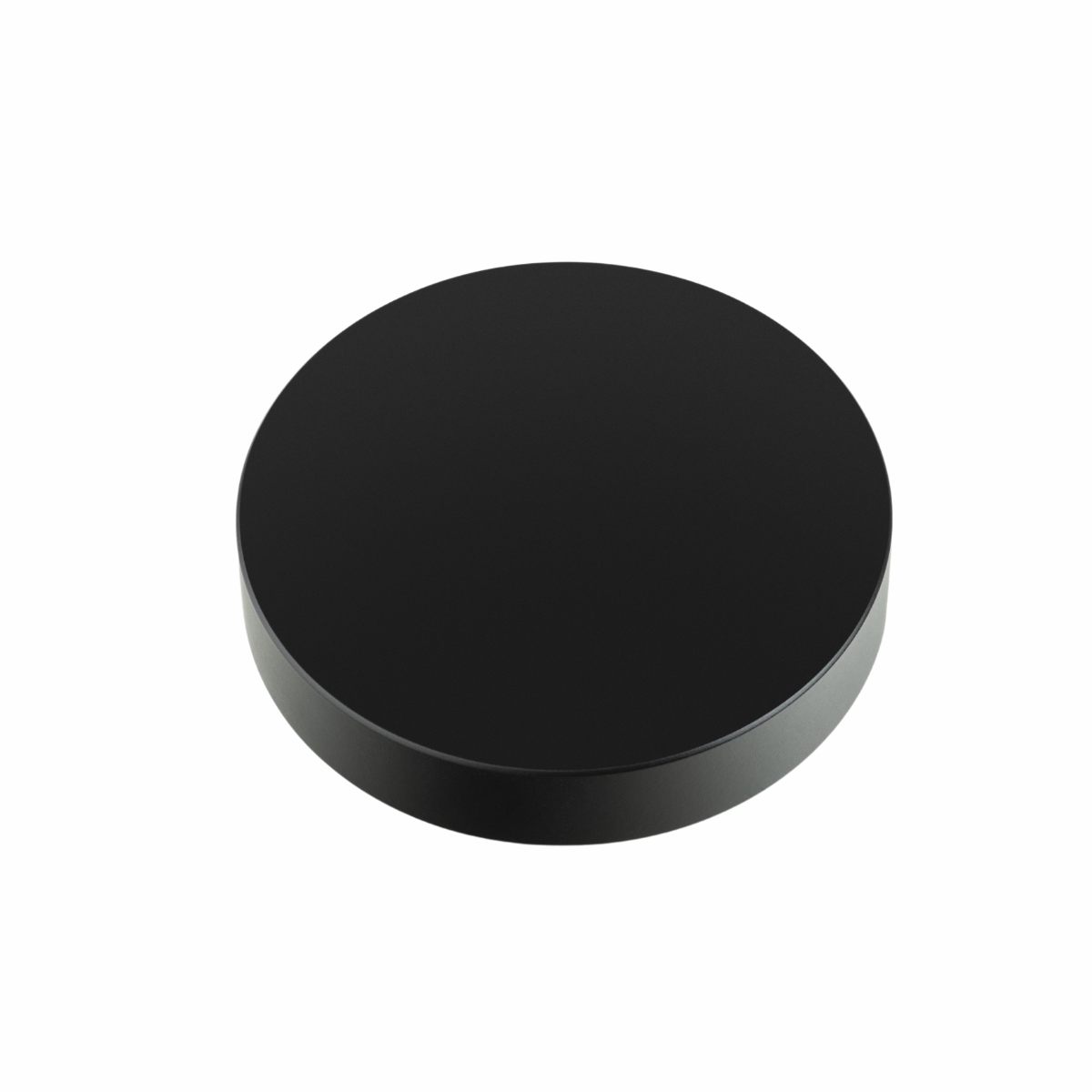 Czarny, okrągły przedmiot z płaskim wierzchem i lekko podniesioną krawędzią, prawdopodobnie pokrywa.