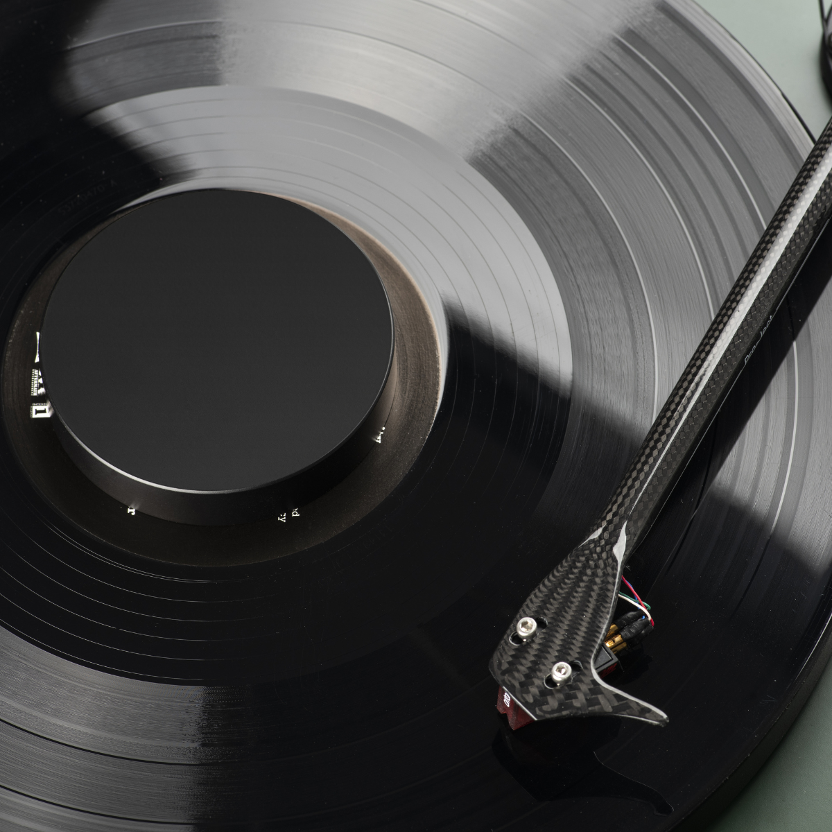 Czarna płyta winylowa na gramofonie. Widoczne ramię. Zielone tło.