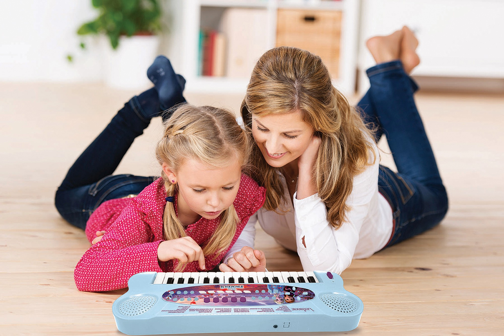 Mujer y niño jugando con un piano de juguete en el suelo de madera.