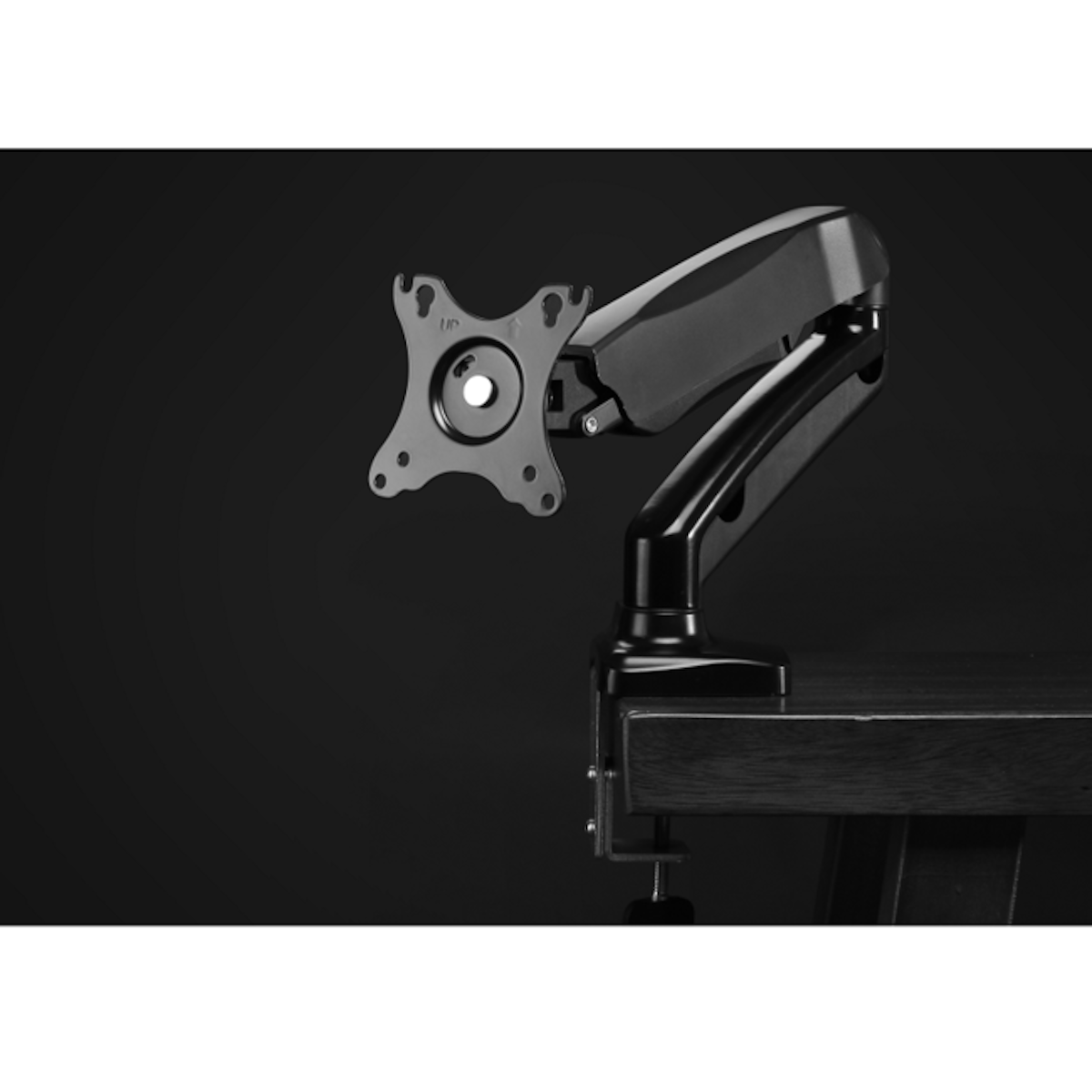 Bras de moniteur noir sur bureau. Support de moniteur argenté fixé. Fond sombre.