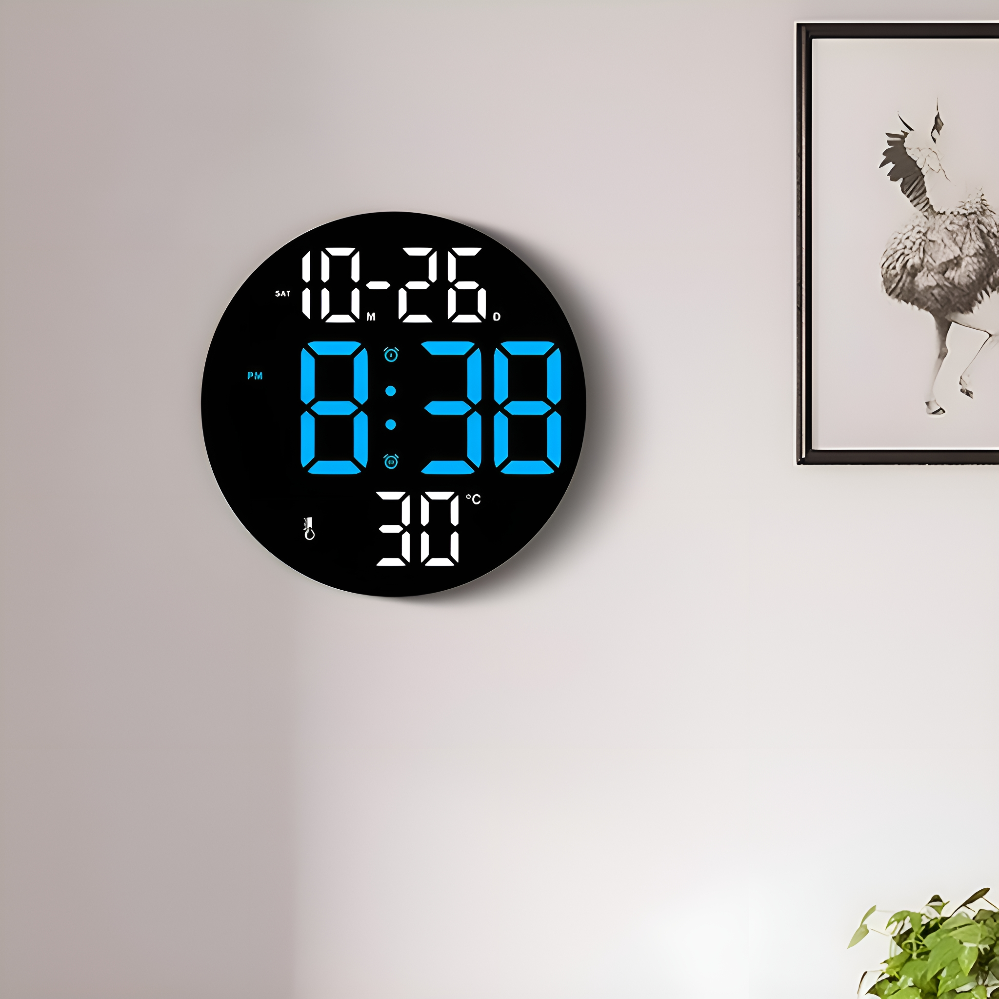 Eine runde, schwarze Digitaluhr an einer weißen Wand zeigt Zeit und Datum in blauen Ziffern an.