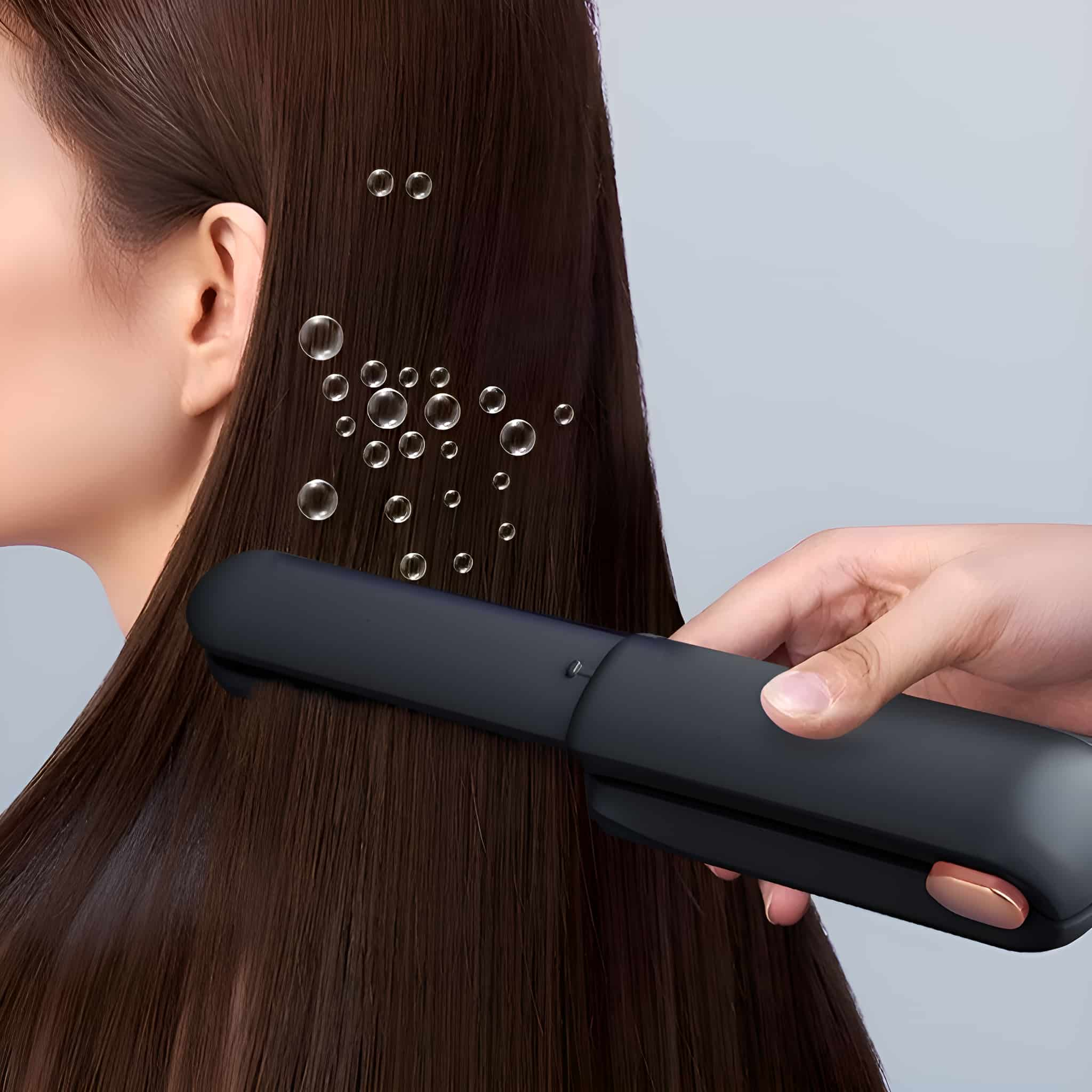 Eine Person benutzt einen schwarzen Haarglätter auf dem braunen Haar einer Frau.