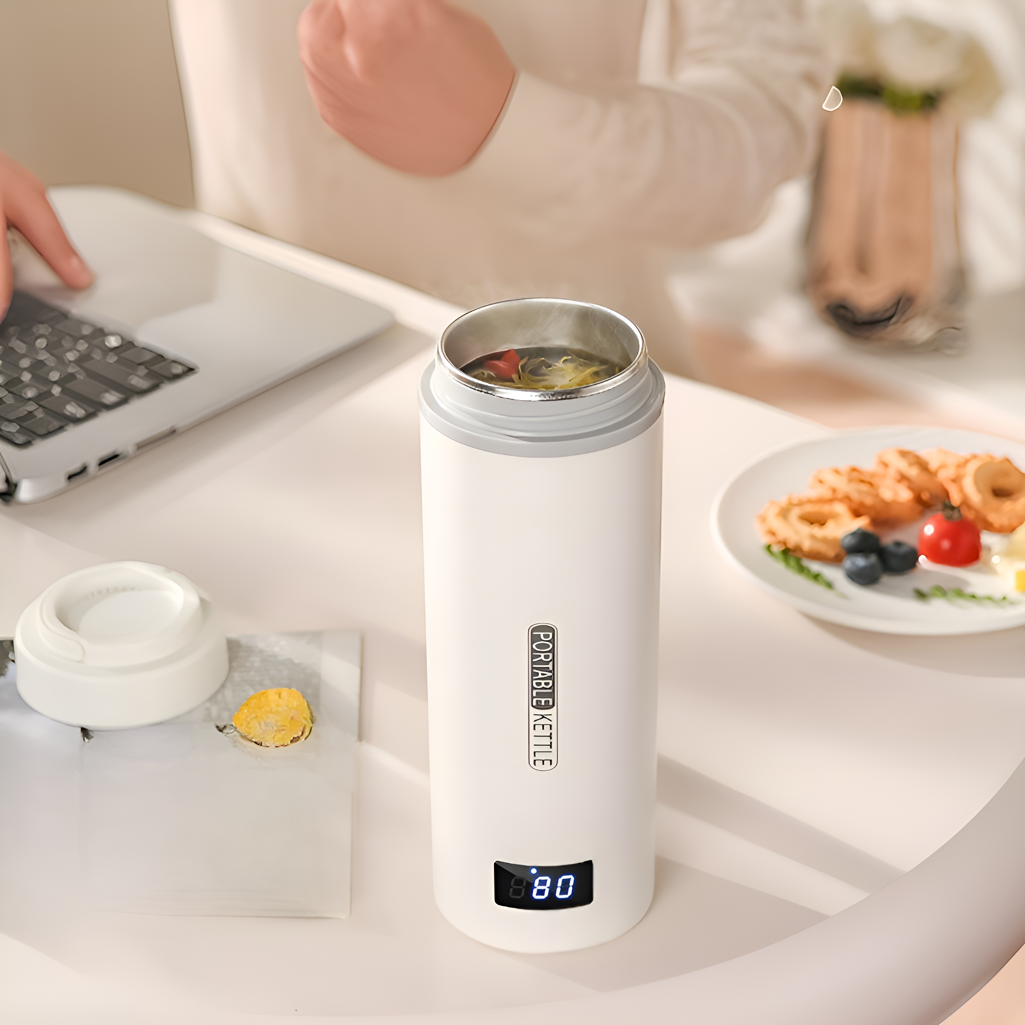 Ein weißer tragbarer Wasserkocher mit digitaler Anzeige, mit Gegenständen auf einem Tisch. Weißer Hintergrund.