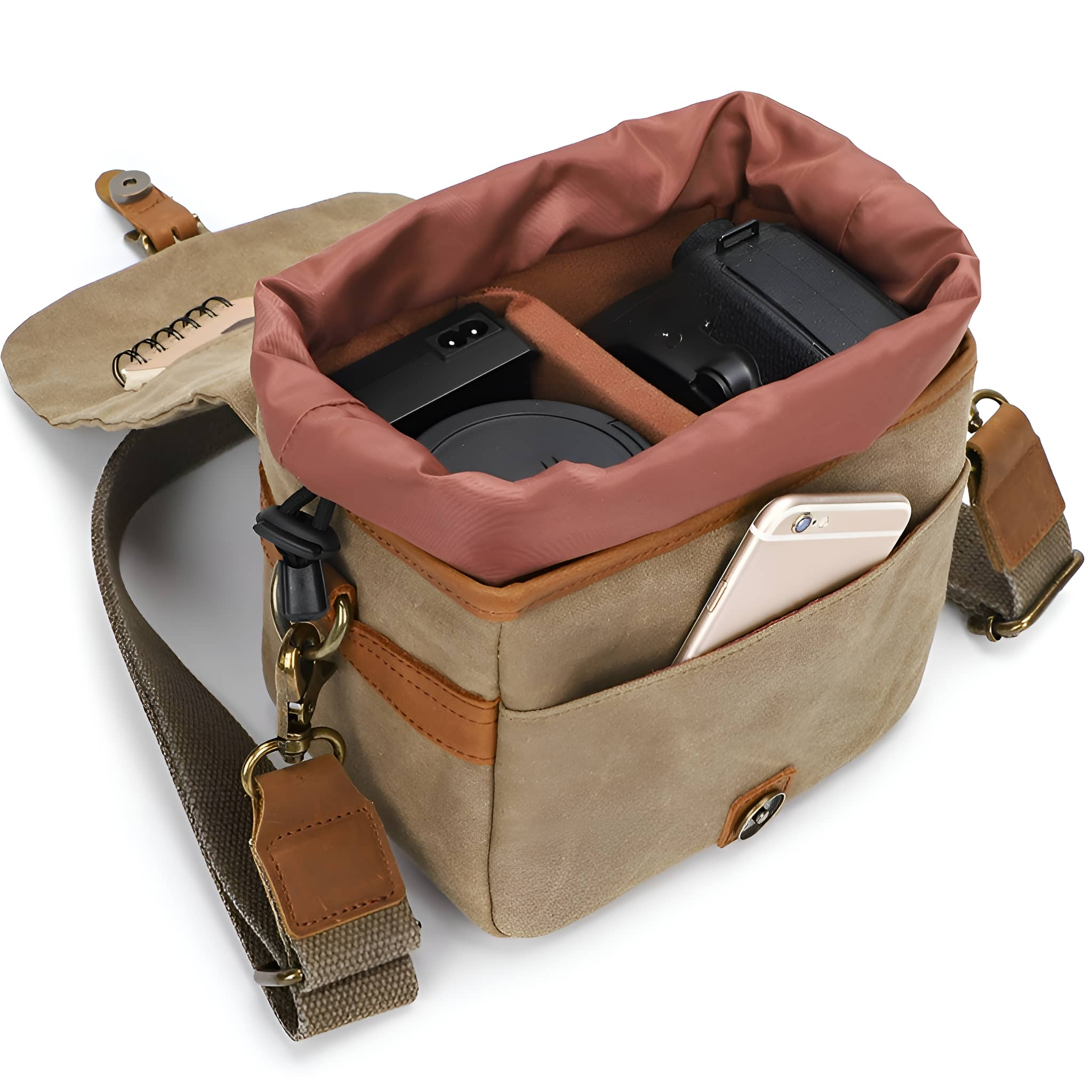 Eine offene beige Kameratasche mit Kamera, Objektiv, Telefon und Gegenständen, auf weißem Hintergrund.