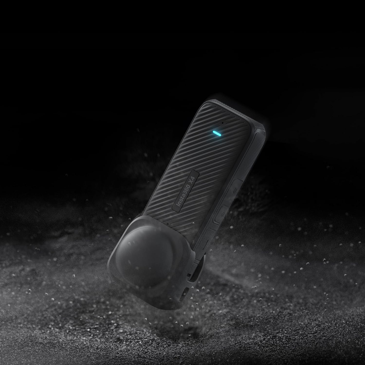 Czarna kamera, Insta360 X4, z ochronnym etui. Ciemne tło z rozproszonymi cząsteczkami pyłu.