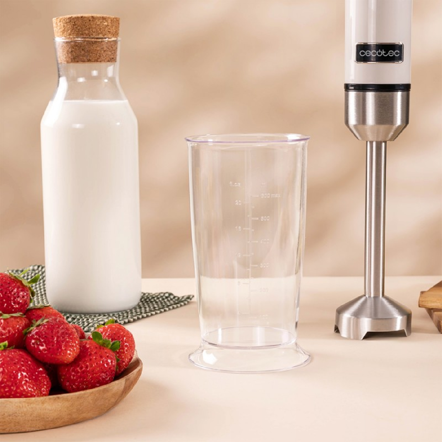 Un frullatore con un contenitore, una bottiglia di latte e fragole disposte su un tavolo.