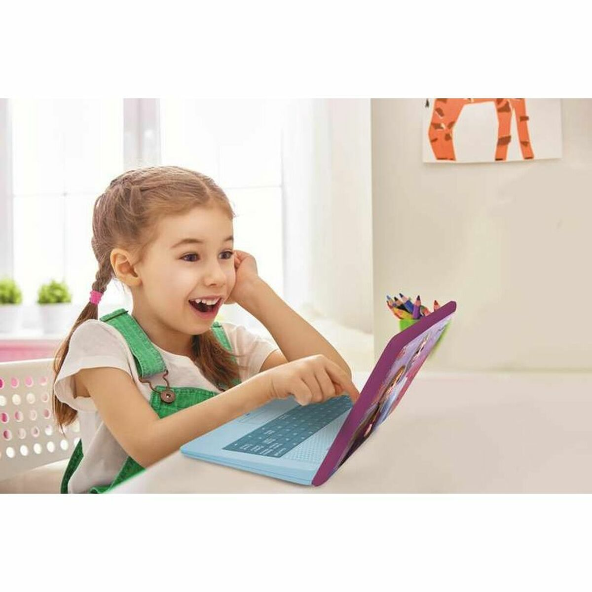 Una niña usando una laptop morada y azul, sonriendo y mirando la pantalla.