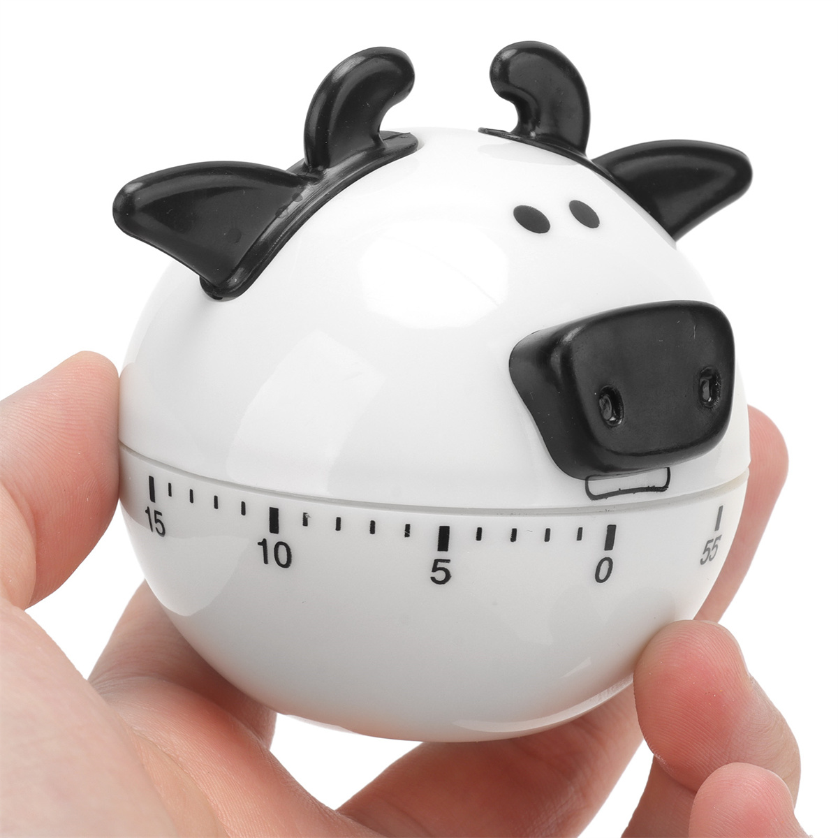 Ein weißer, kuhförmiger Küchentimer mit schwarzen Akzenten, in der Hand einer Person, die die Zeit anzeigt.