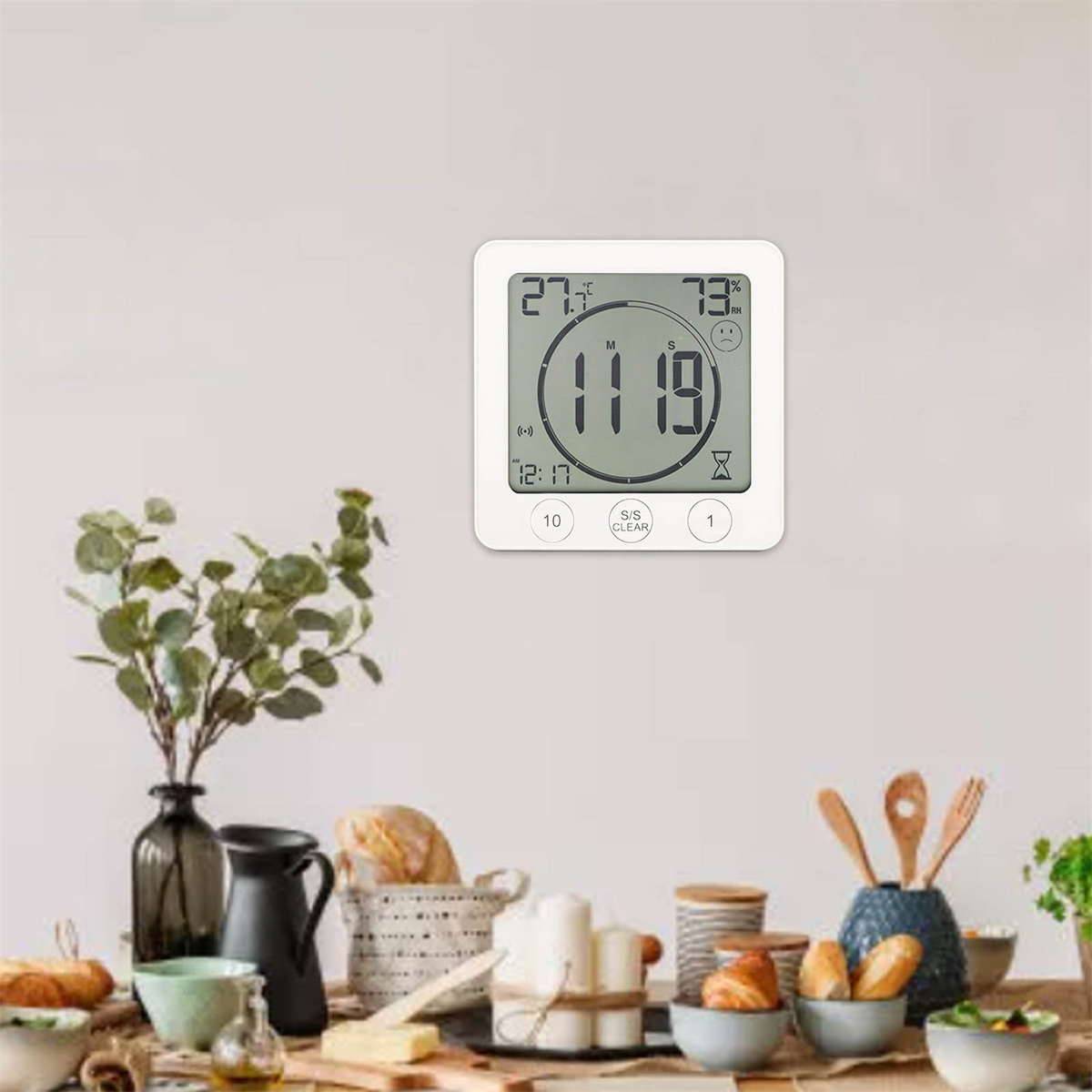 Digitaler Timer mit Zeit und Temperatur, auf einem Tisch mit Lebensmitteln.