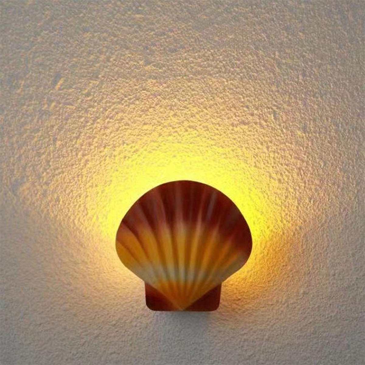 Eine muschelförmige Lampe. Das Licht strahlt aus der Mitte und beleuchtet die Wand.