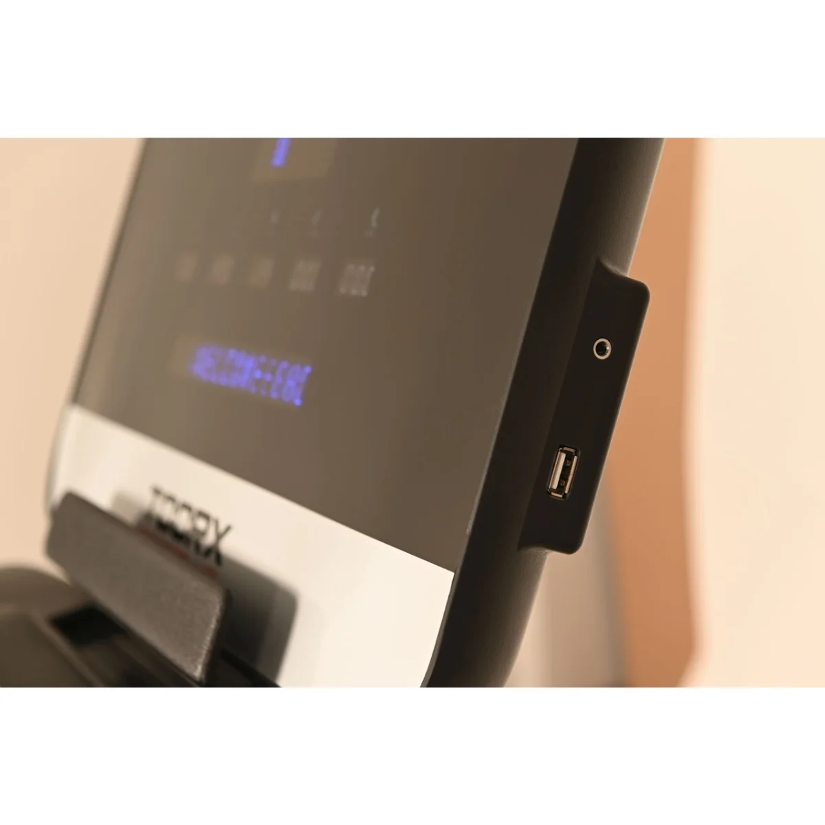 Treadmill control panel with a USB port and a headphone jack, on a beige background.