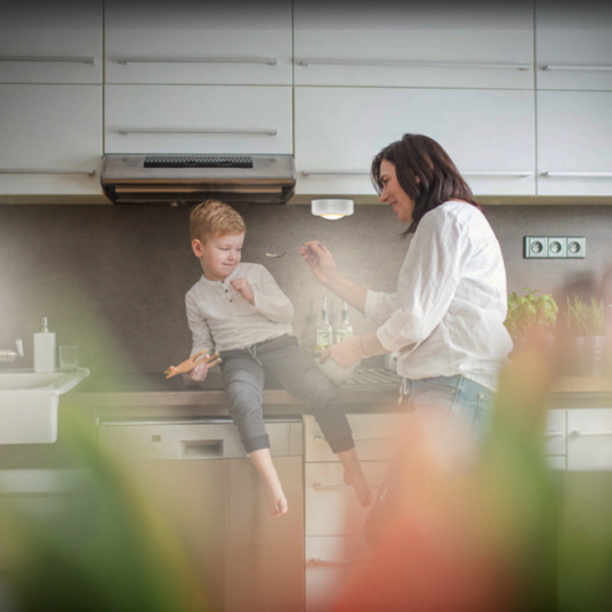 Una mujer alimenta a un niño en una cocina brillante y moderna.