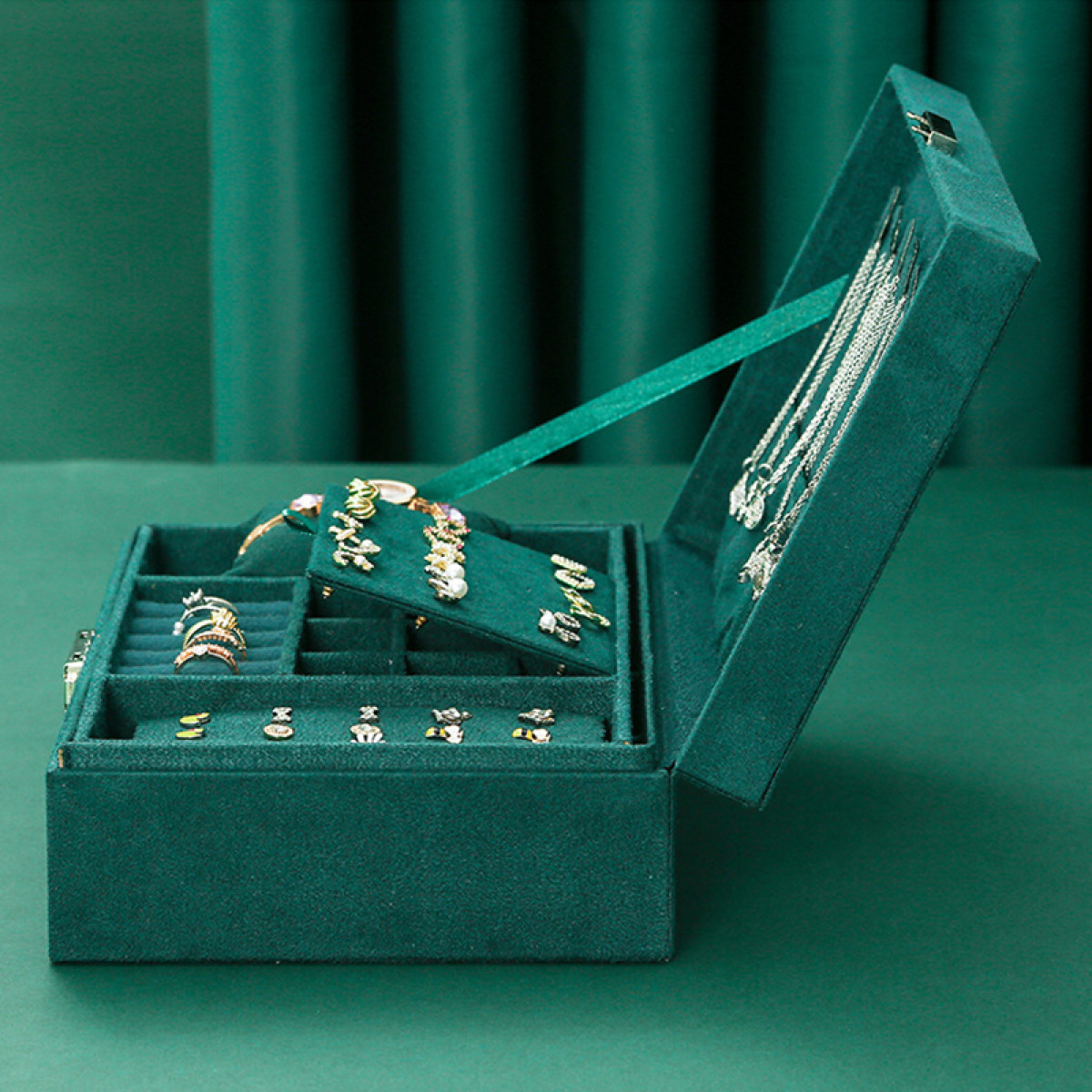 Geöffnete teal Schmuckschatulle gefüllt mit Ringen, Ohrringen und Halsketten.