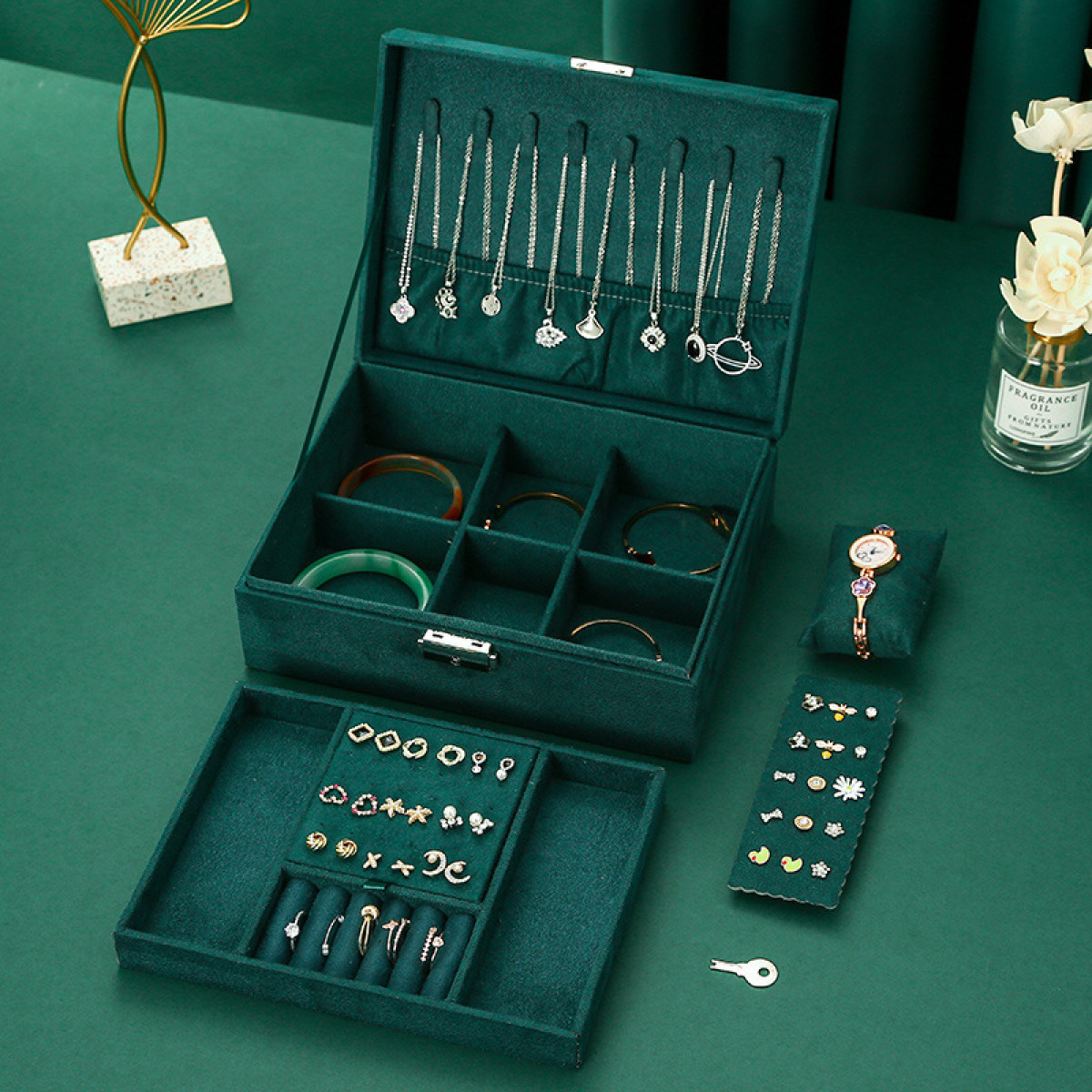 Geöffnete Schmuckschatulle mit Halsketten, Armbändern, Ringen und einer Uhr.