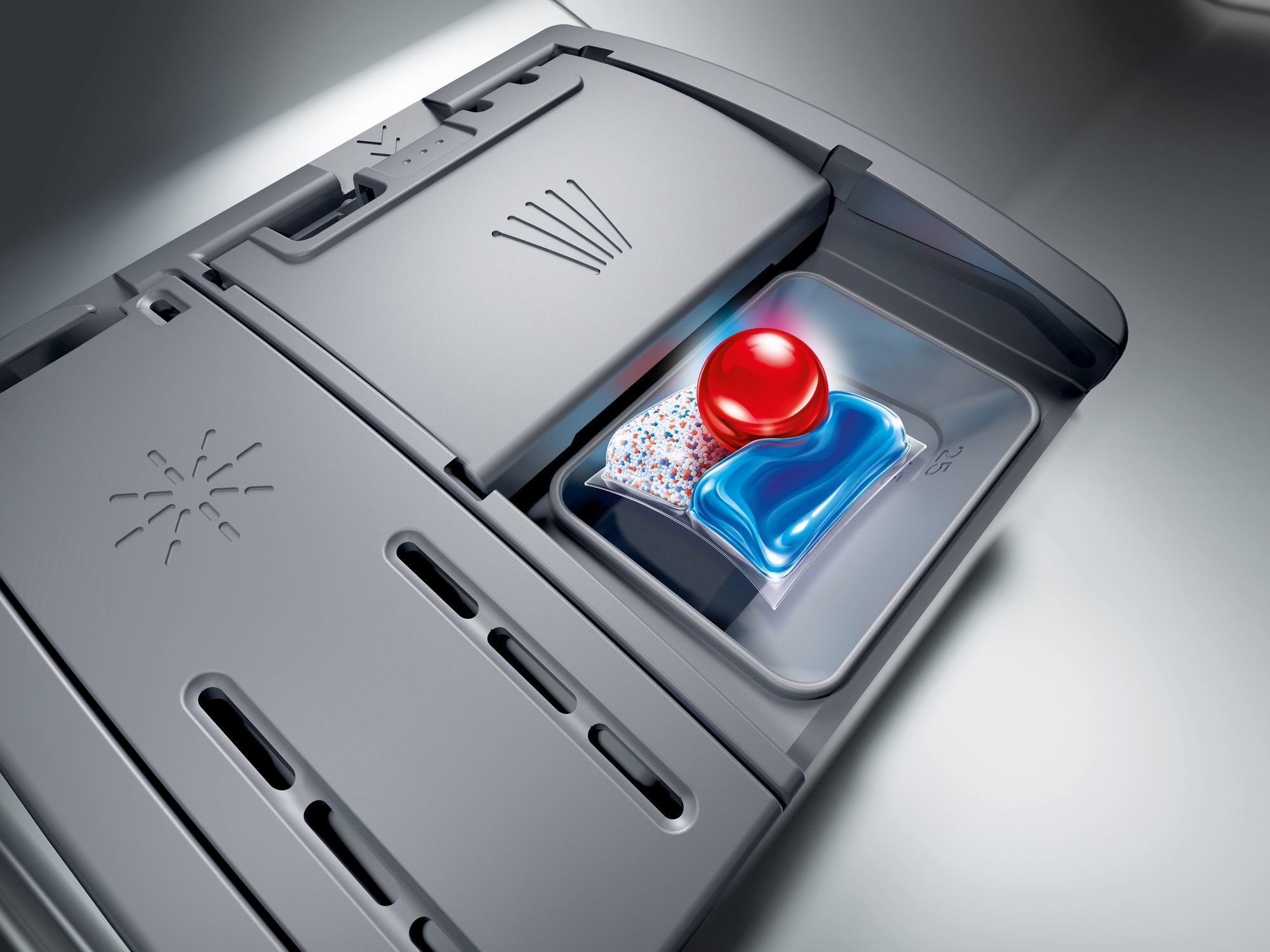 Ein Geschirrspülfach mit einem Spülmittel-Pod. Der Hintergrund ist grau.