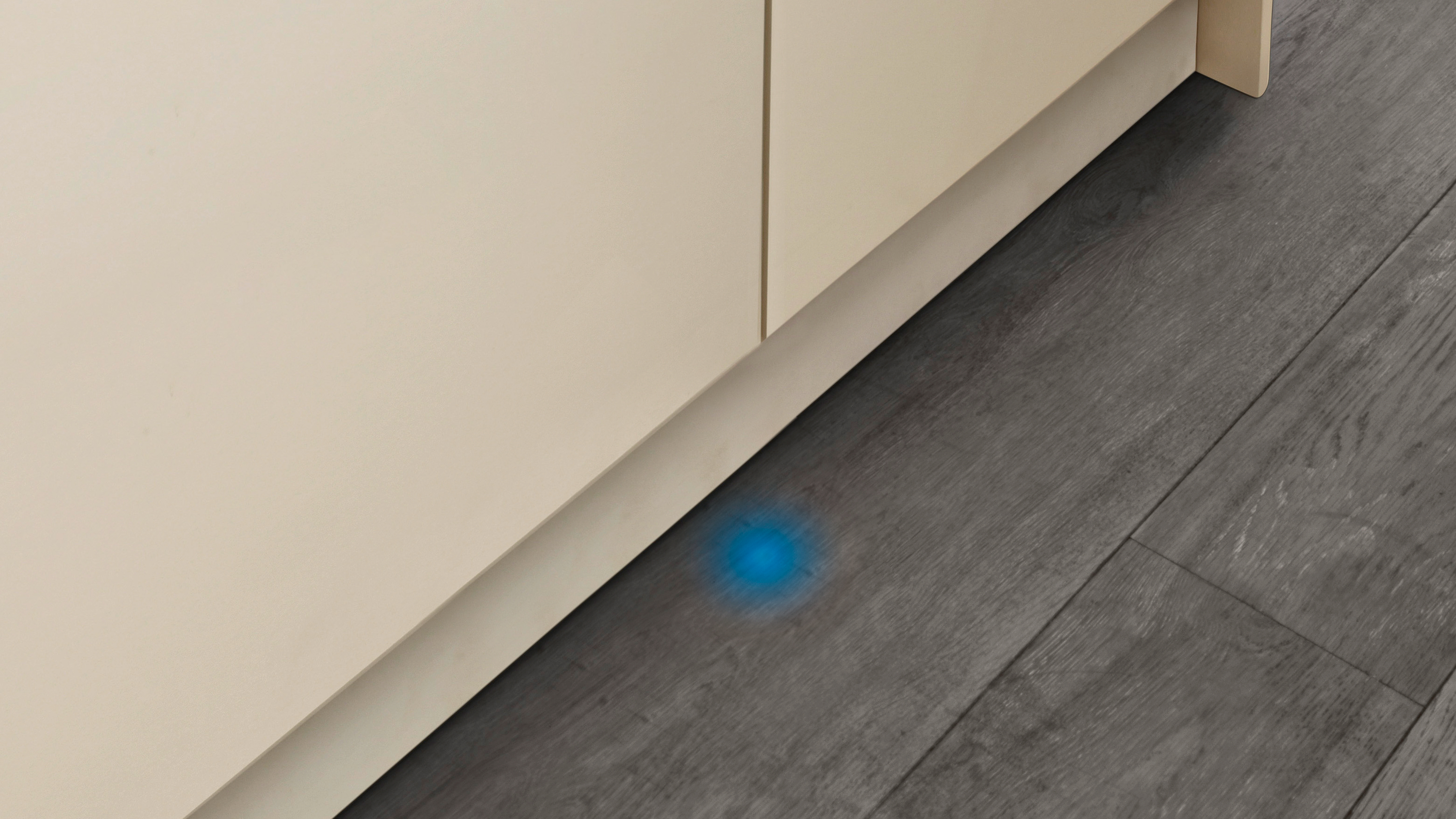 Un armario de cocina con un suelo gris oscuro y una mancha de luz azul.