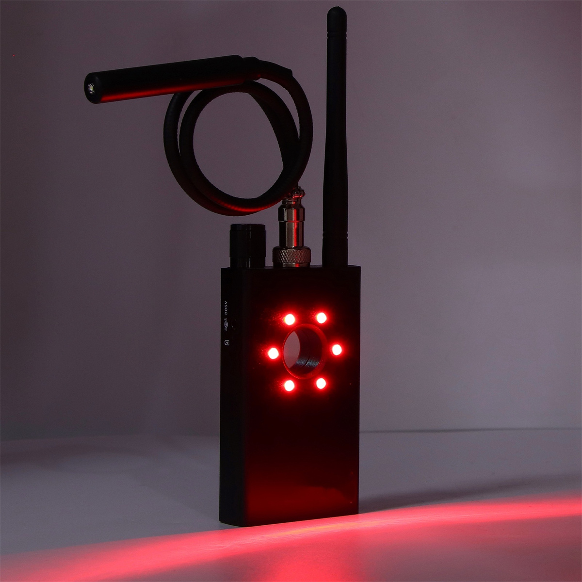 Ein schwarzes Gerät mit roten Lichtern, einer langen Antenne und einem flexiblen Licht. Der Hintergrund ist dunkel.