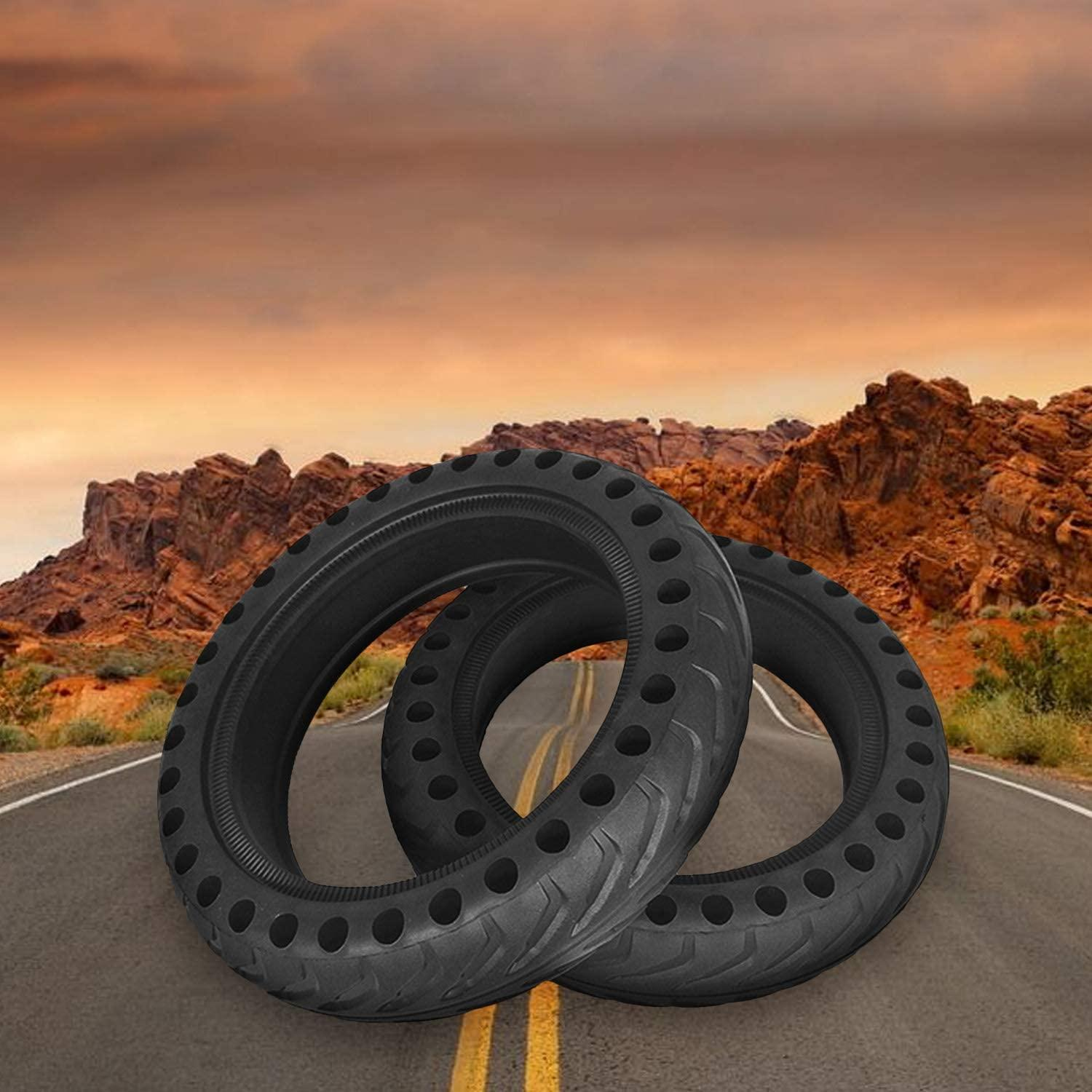 Dwie czarne opony do skutera z otworami, na drodze z tłem krajobrazu pustynnego.
