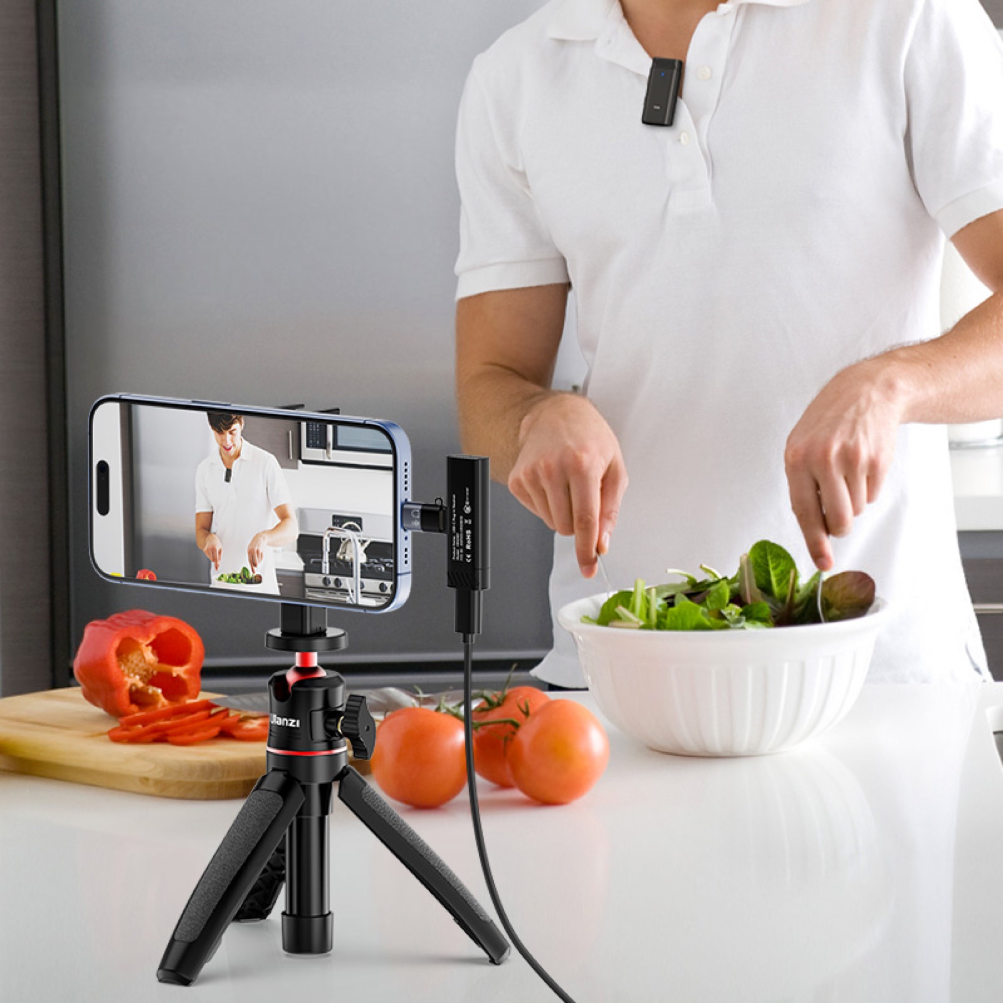 A person filming a cooking demonstration with a phone, a microphone, and ingredients on a counter.
