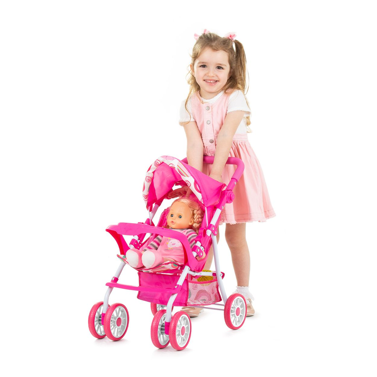 Ein Mädchen in rosa Kleid schiebt einen rosa Puppenwagen mit einer Puppe darin.