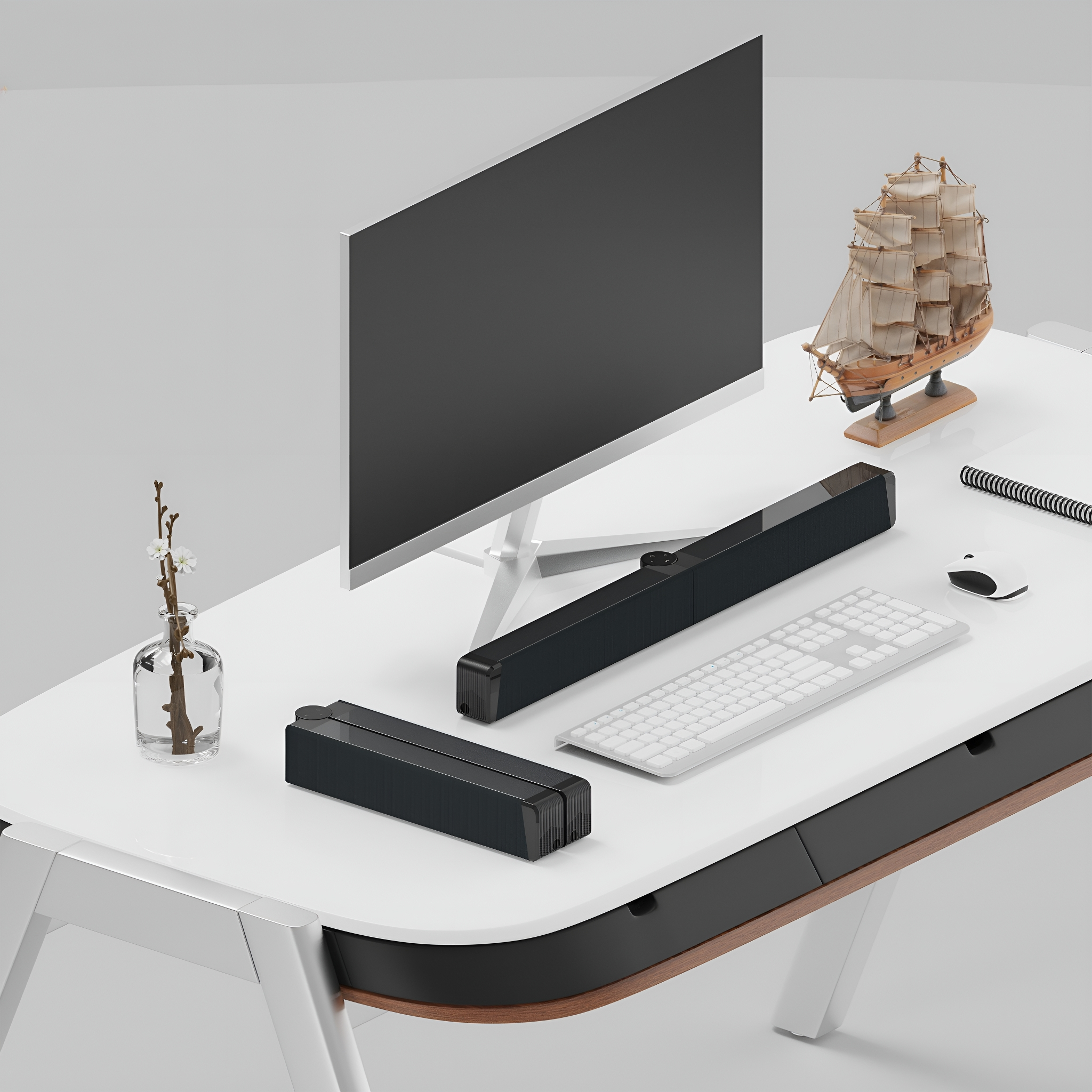 Ein Schreibtisch mit Computer, Soundbar und Schiffsmodell. Weiße, schwarze und braune Farben.