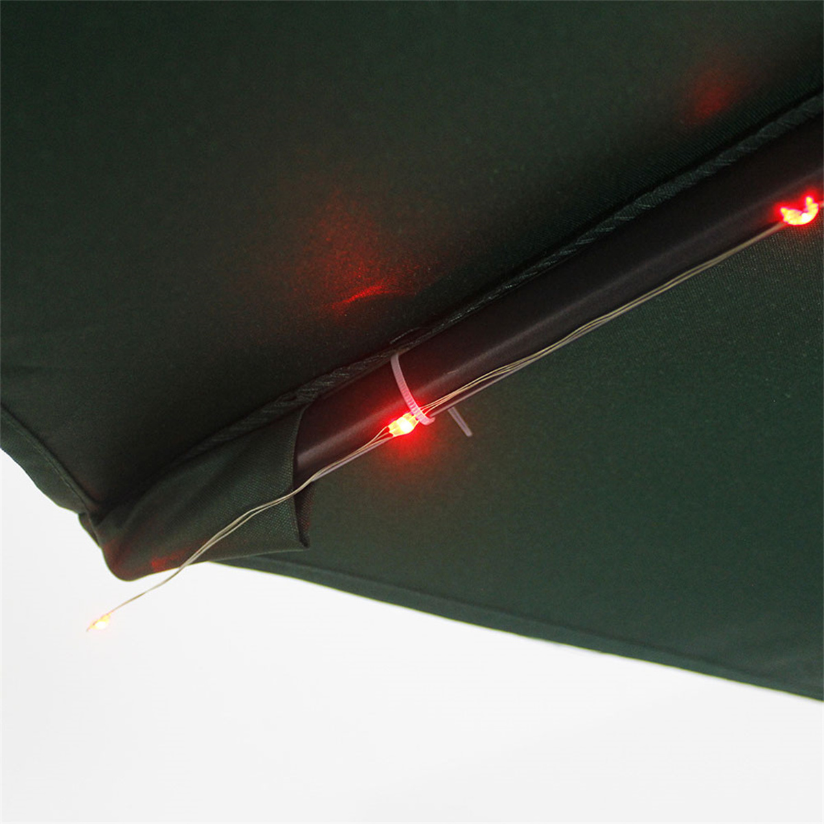Nahaufnahme eines dunkelgrünen Regenschirms mit roten LED-Leuchten und einem weißen Kabel.