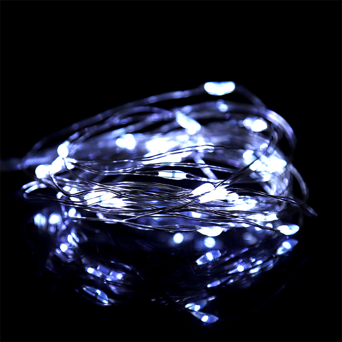 Aufgerollte Lichterkette mit kleinen weißen LEDs. Schwarzer Hintergrund mit Reflexion.