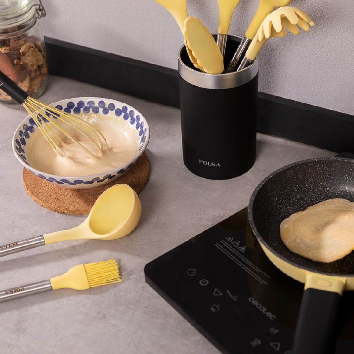 Escena de cocina con utensilios de cocina y comida, sobre una encimera negra.
