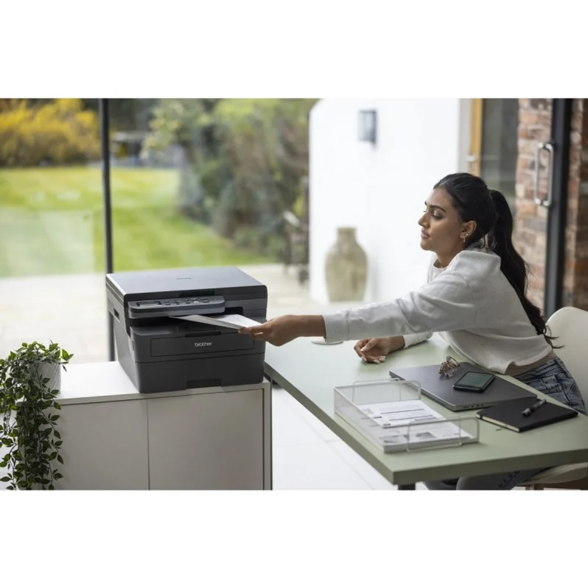 Kobieta wkłada papier do drukarki Brother w biurze.