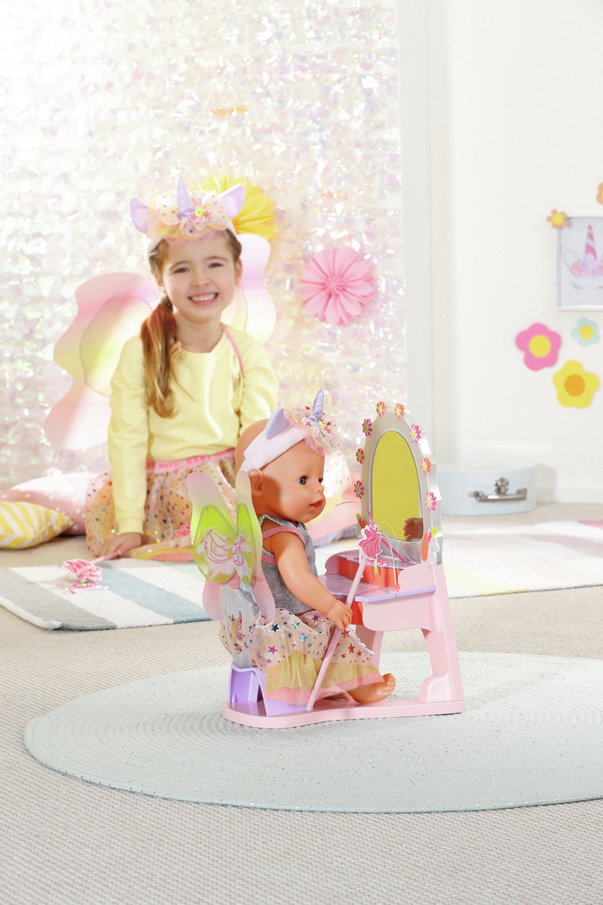 Ein Mädchen und eine Puppe an einem Schminktisch, beide mit Einhorn-Stirnbändern.