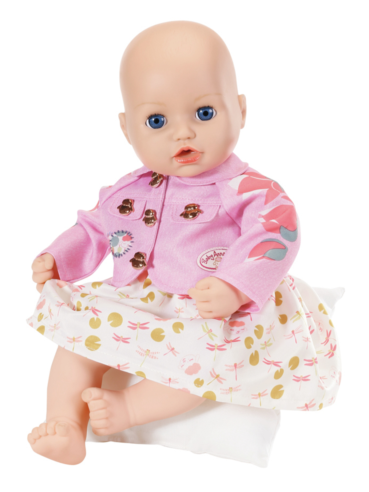 Eine Puppe mit rosa Jacke und Rock, sitzt auf einem Kissen.