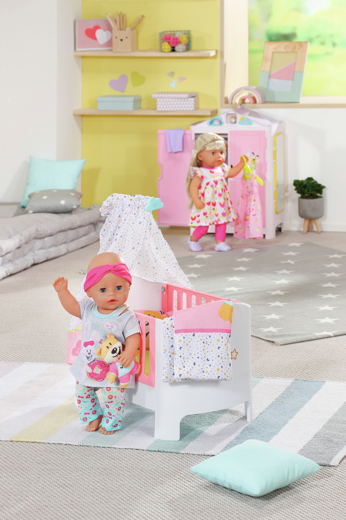 Zwei Puppen in einem Raum. Eine im Kinderbett, die andere am Schrank.