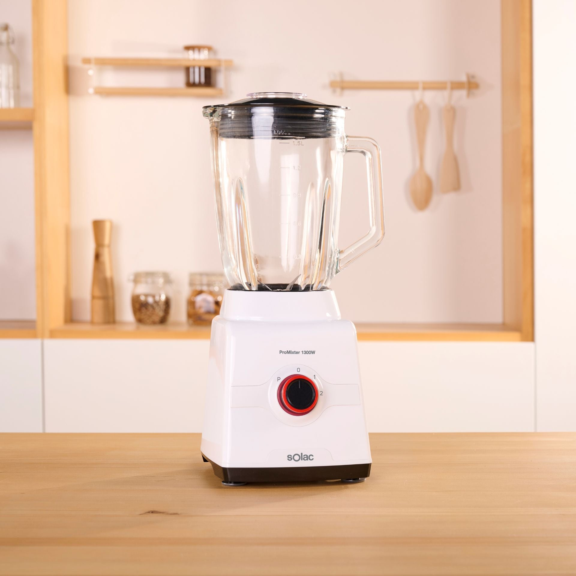 Una licuadora blanca con un tarro de vidrio. Está sobre una superficie de madera en una cocina.