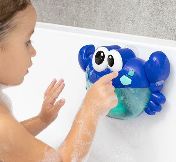 Ein Kind spielt in einer Badewanne mit einem blauen, krabbenförmigen Badespielzeug.