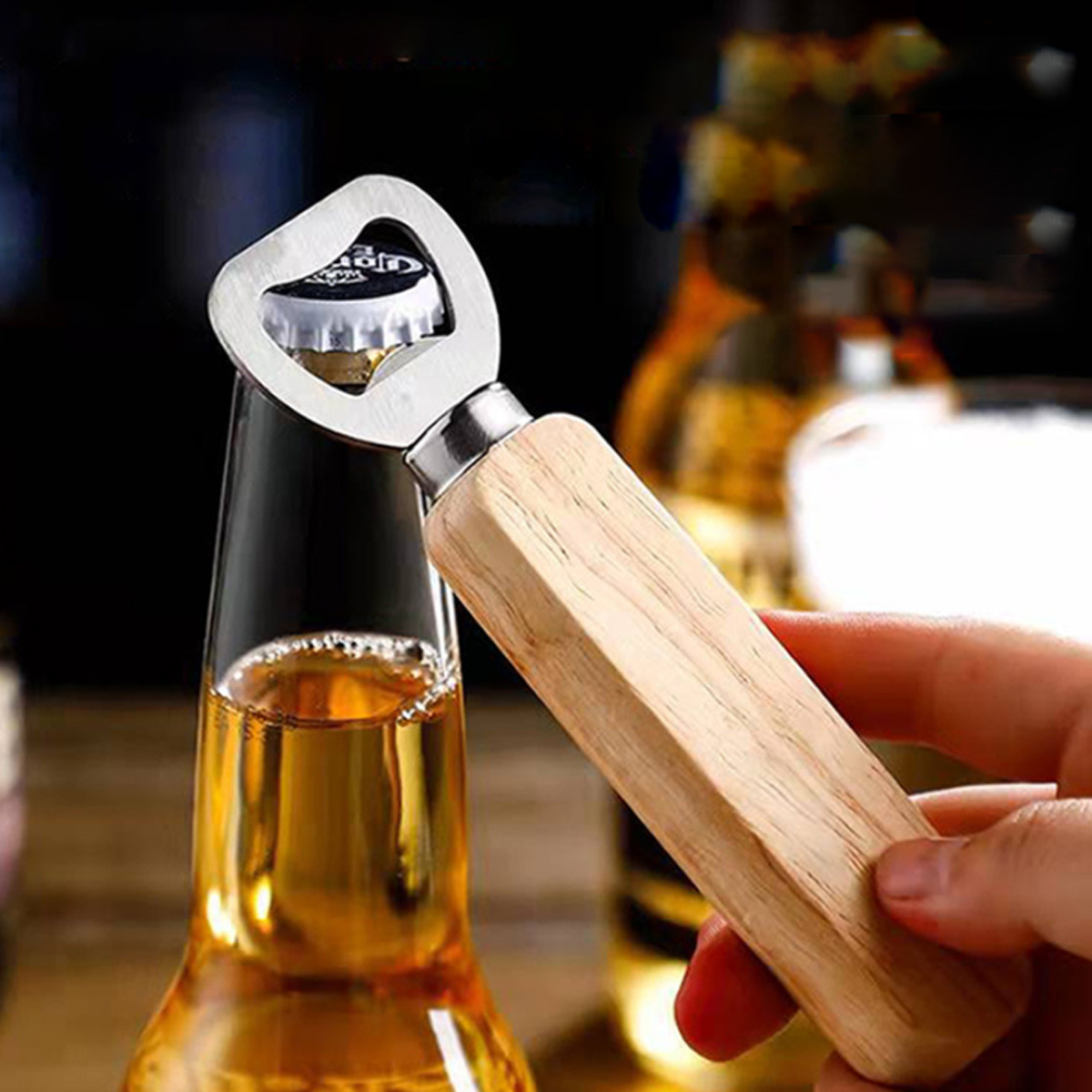 Eine Bierflasche mit einem Flaschenöffner, der die Kappe entfernt, gehalten von einer Hand.