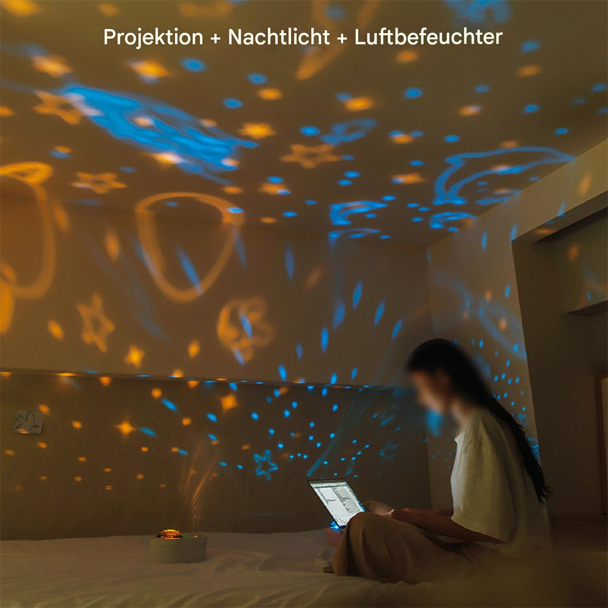Eine Frau benutzt einen Laptop, mit Sternen, die an Decke und Wände projiziert werden.