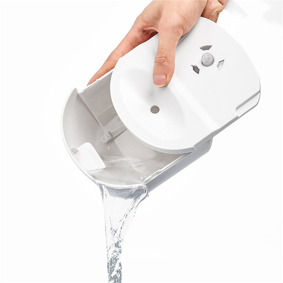Eine Hand, die Wasser aus einem weißen Behälter mit Aussparungen gießt. Weißer Hintergrund.