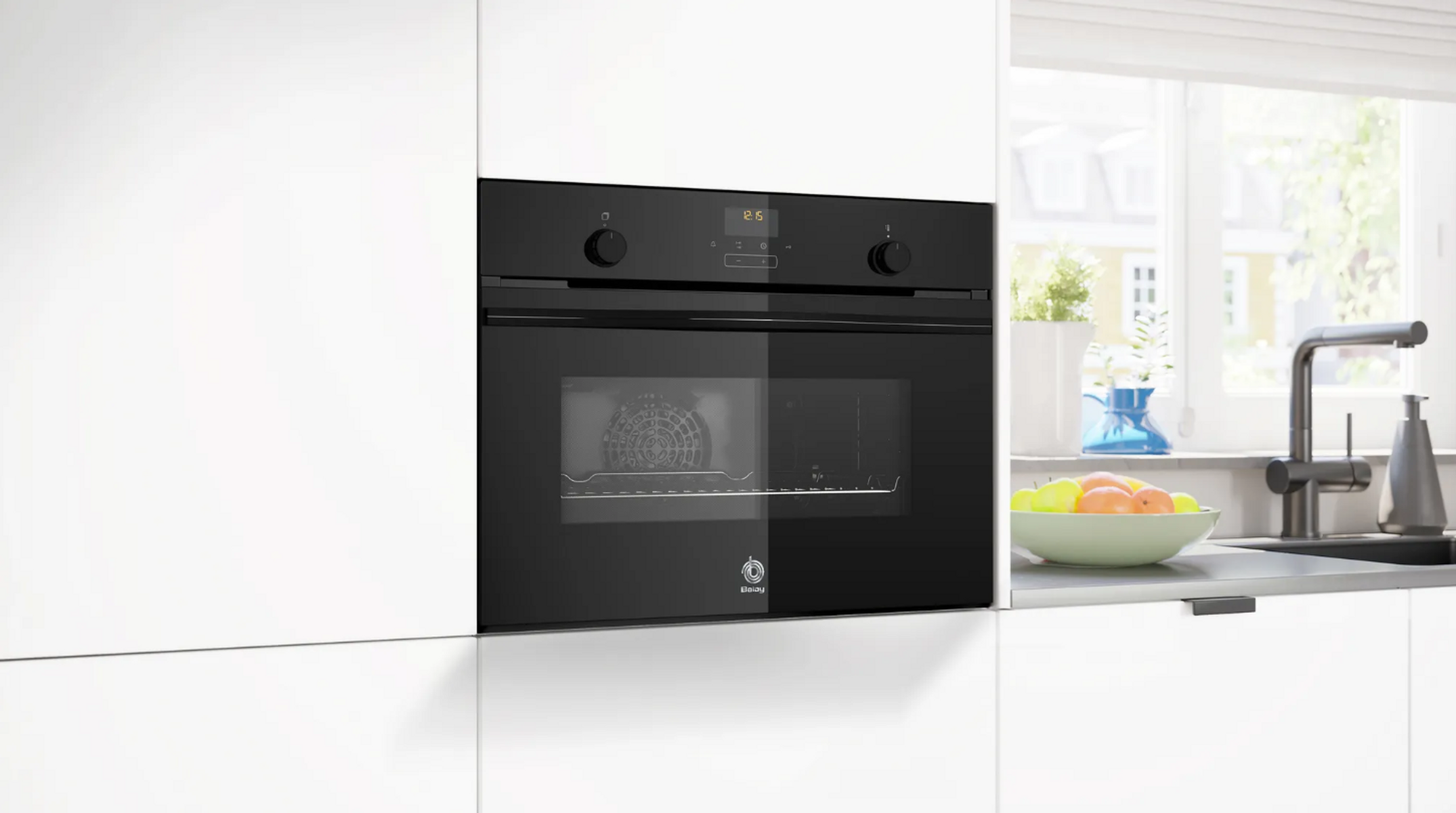 Un horno negro empotrado en una cocina blanca. Está empotrado en la encimera con diales y una pantalla digital.