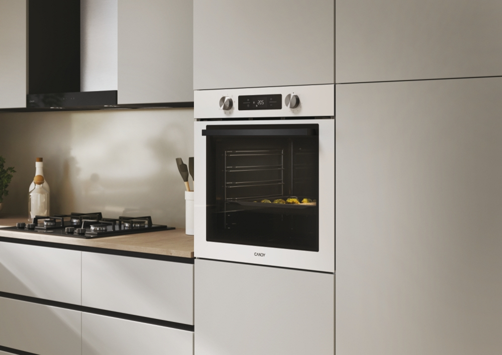 Forno a incasso in cucina. Forno bianco. Cucina grigio chiaro. Piano cottura nero a sinistra.