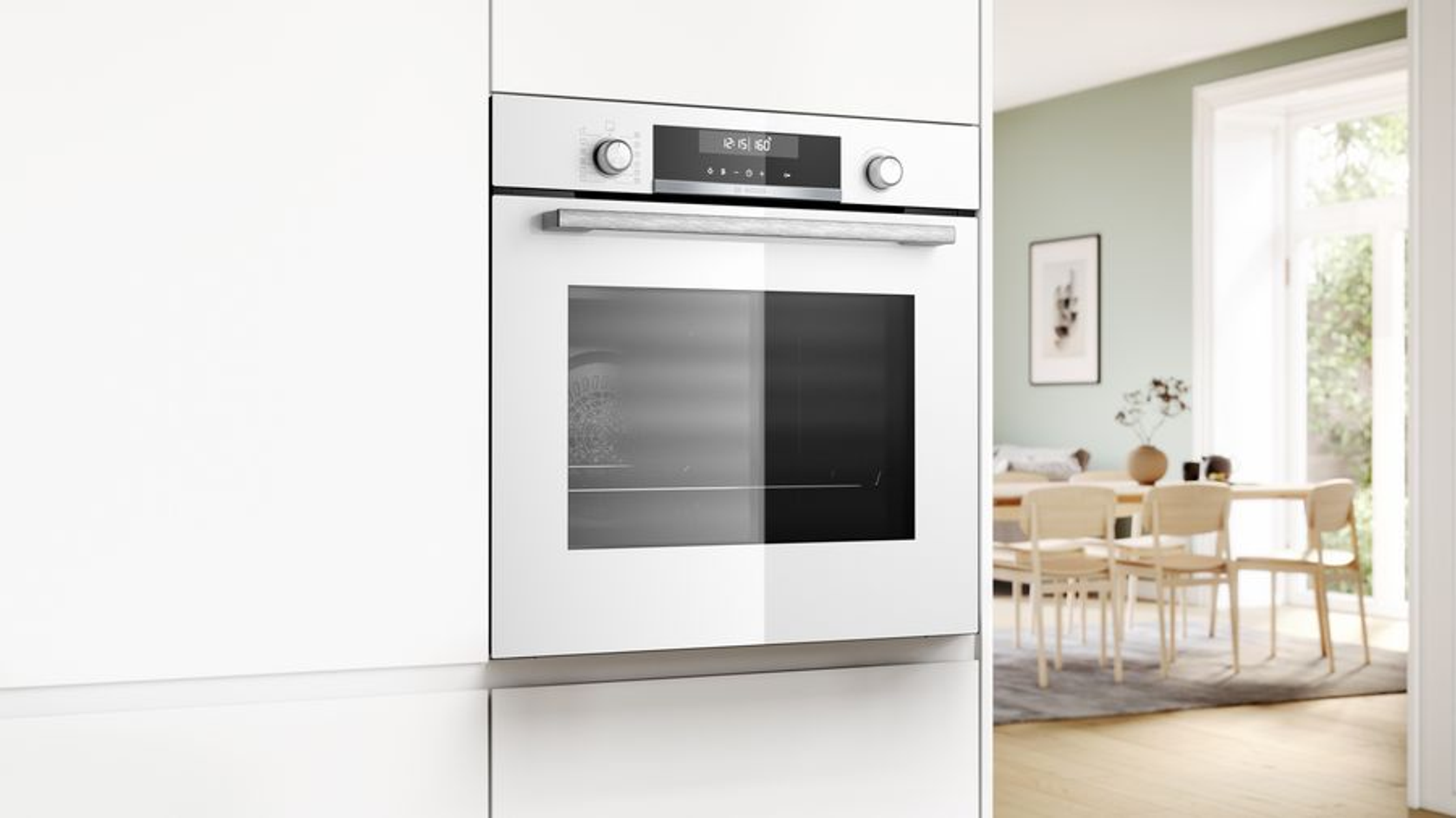 Horno blanco empotrado con pantalla digital, en cocina blanca. Comedor al fondo.