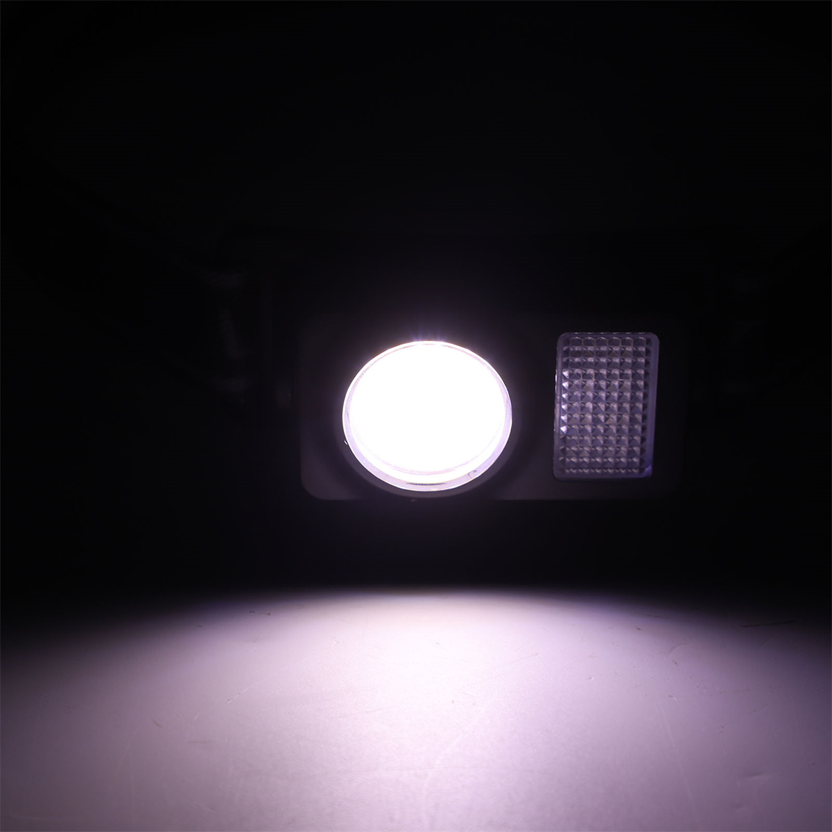 Eine helle Lichtquelle in dunkler Umgebung. Neben dem Licht befindet sich ein kleines rechteckiges Panel.